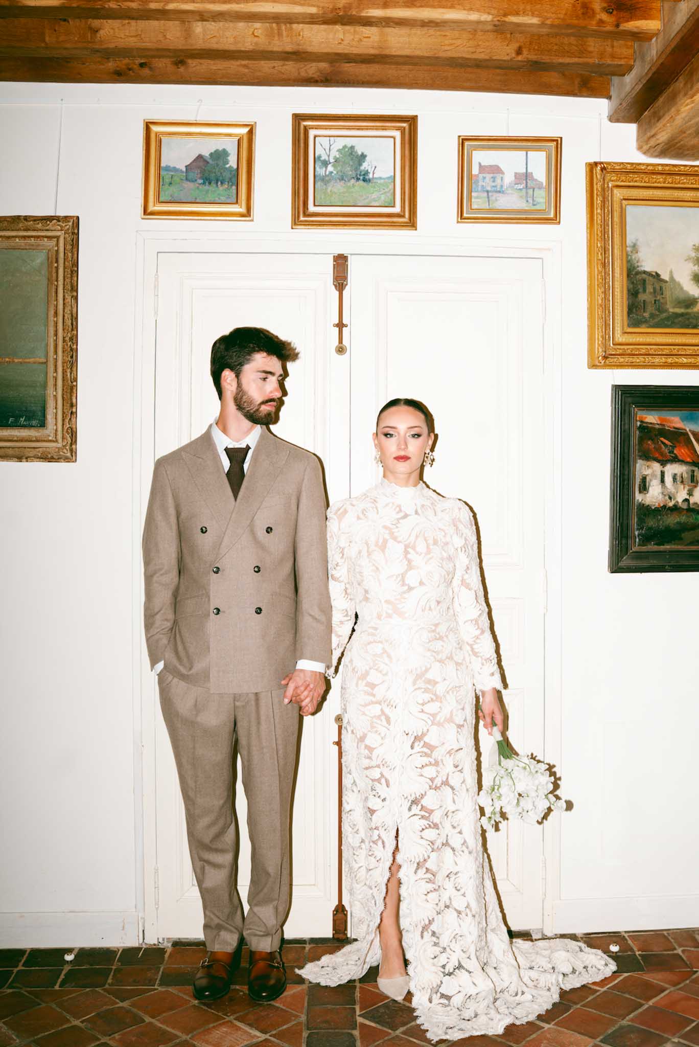 Bride and groom formal portrait in classical interior with exposed beams and artwork