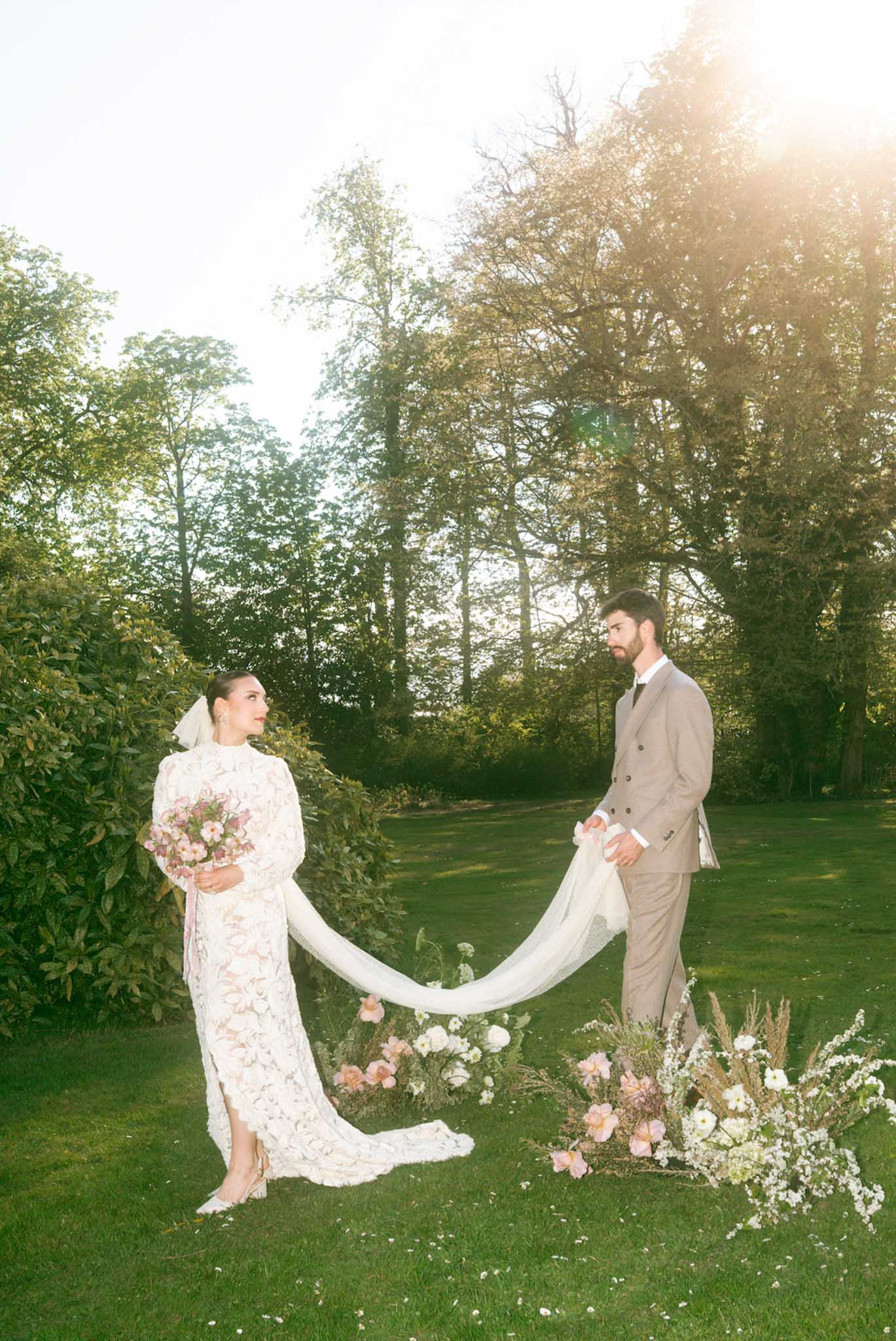 Bride and groom portrait with floral installation in garden setting during golden hour