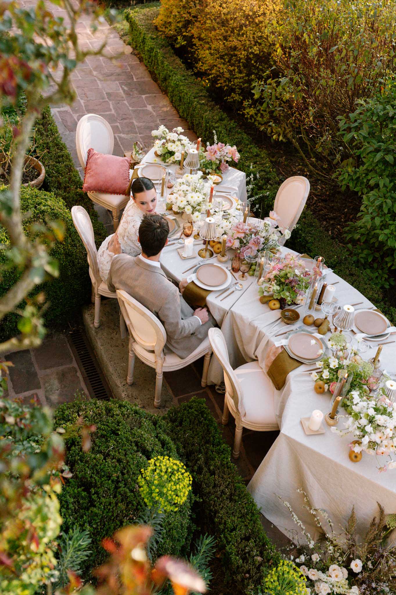 Couple dining at garden reception table with floral centerpieces and elegant place settings
