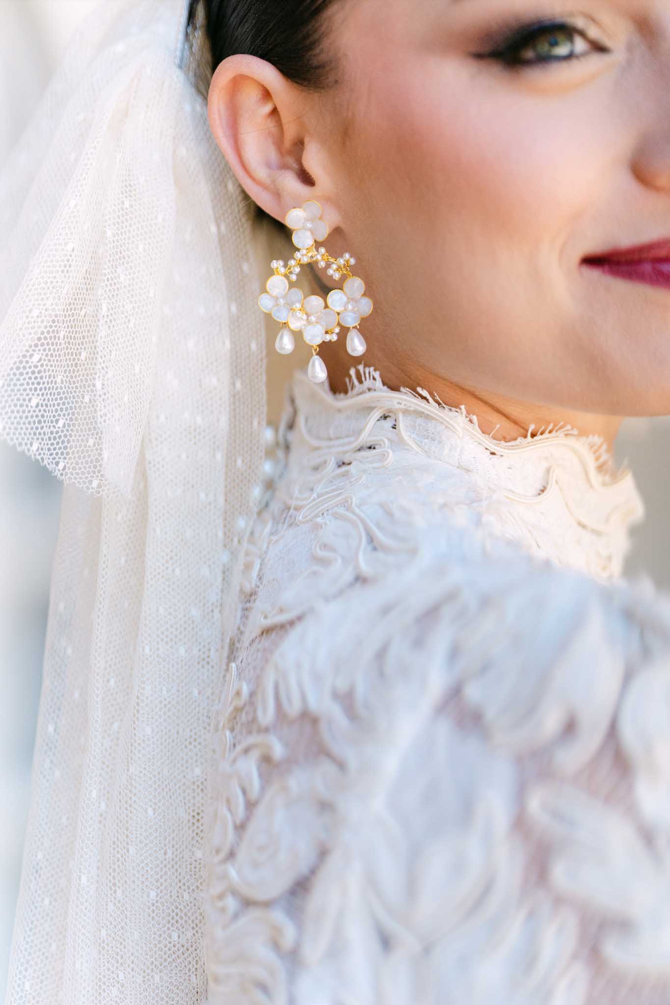 Bride wearing chandelier earrings and ivory veil with beaded gown during wedding portrait session