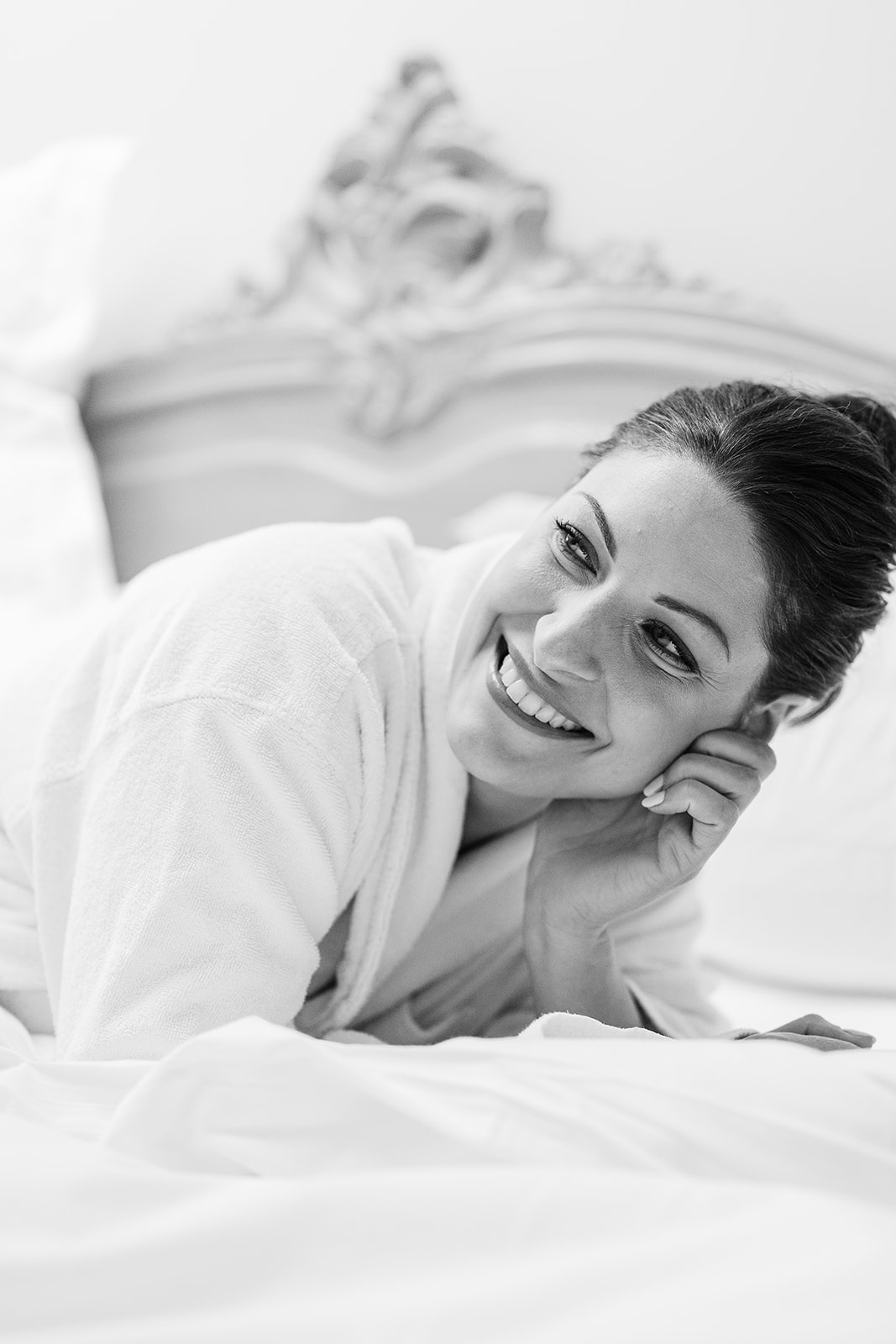 Bride in wedding dress reclining on bed during getting ready moment