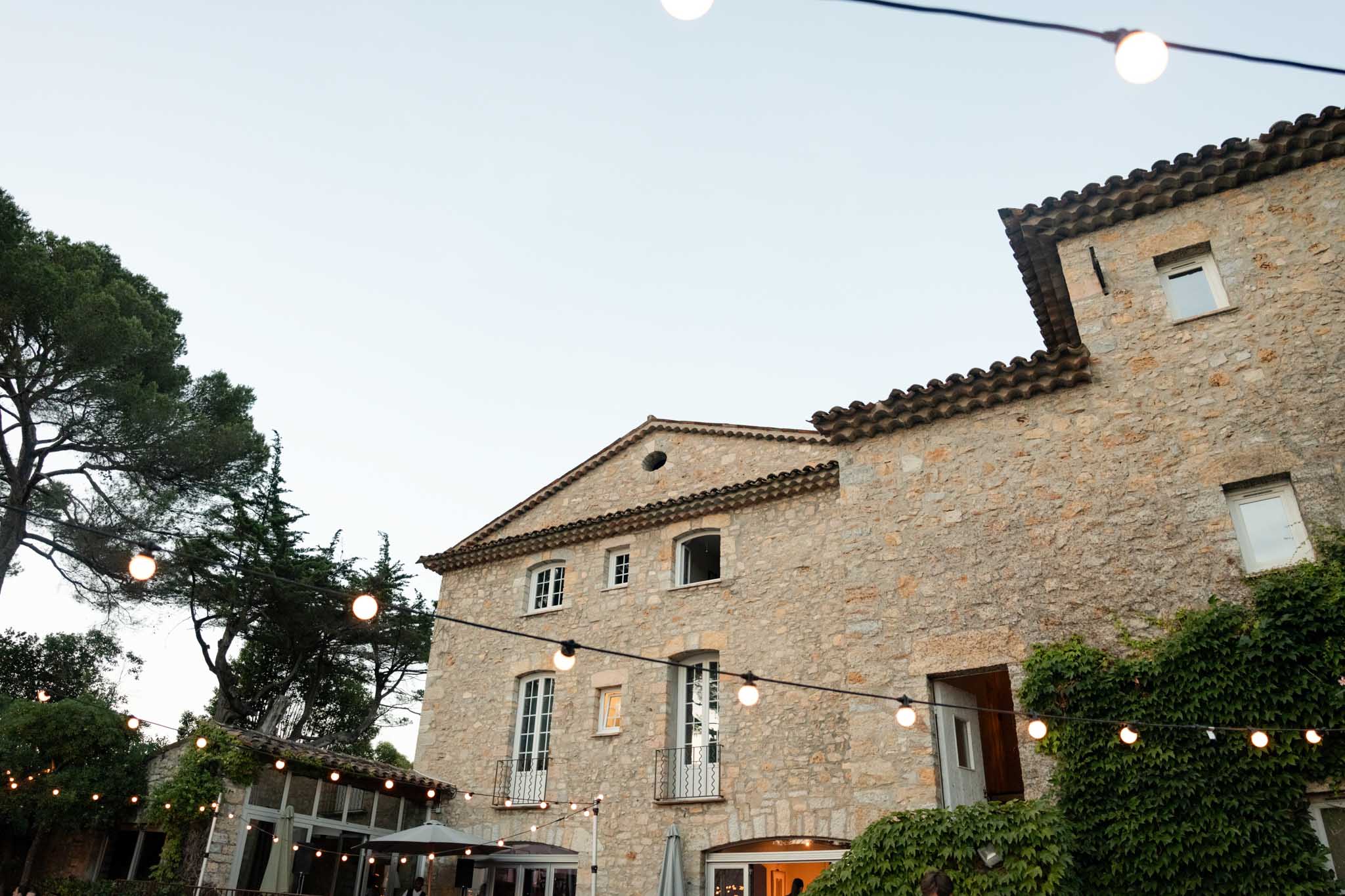 Stone mas facade at dusk with string lights across the courtyard and climbing ivy