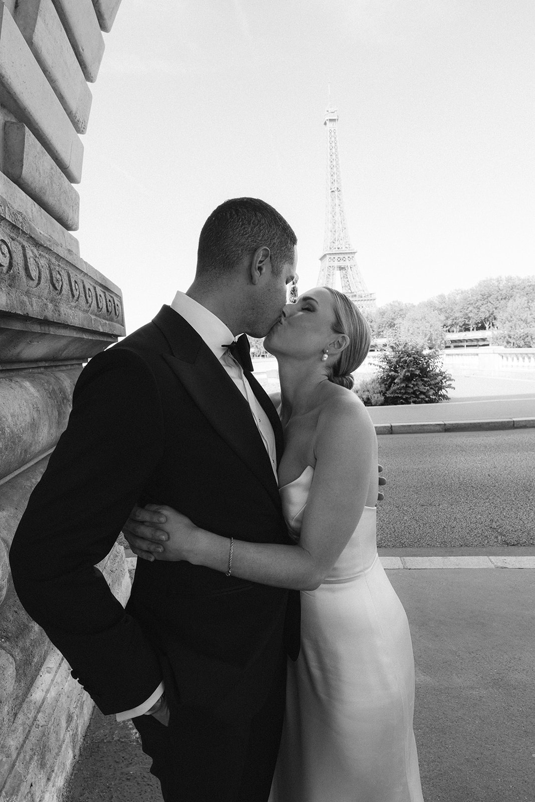 Black and white portrait of the couple kissing with the Eiffel Tower behind them in Paris