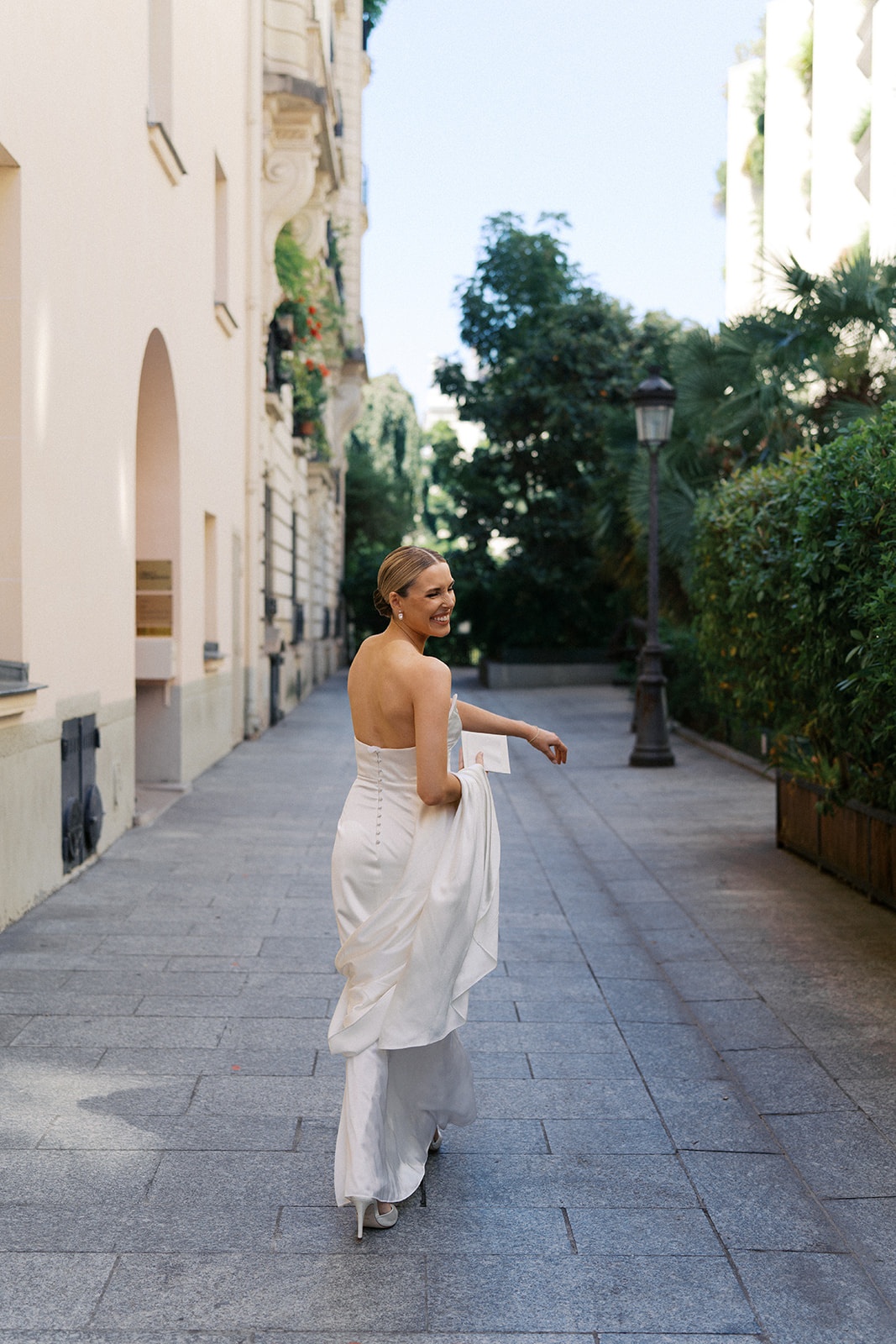Bride glances back over her shoulder while walking a Paris side street in her ivory gown