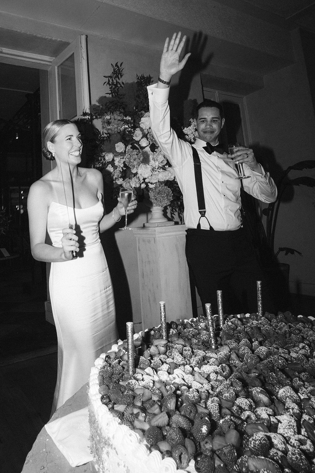 Black and white shot of the couple beside a chocolate-strawberry croquembouche cake at the reception