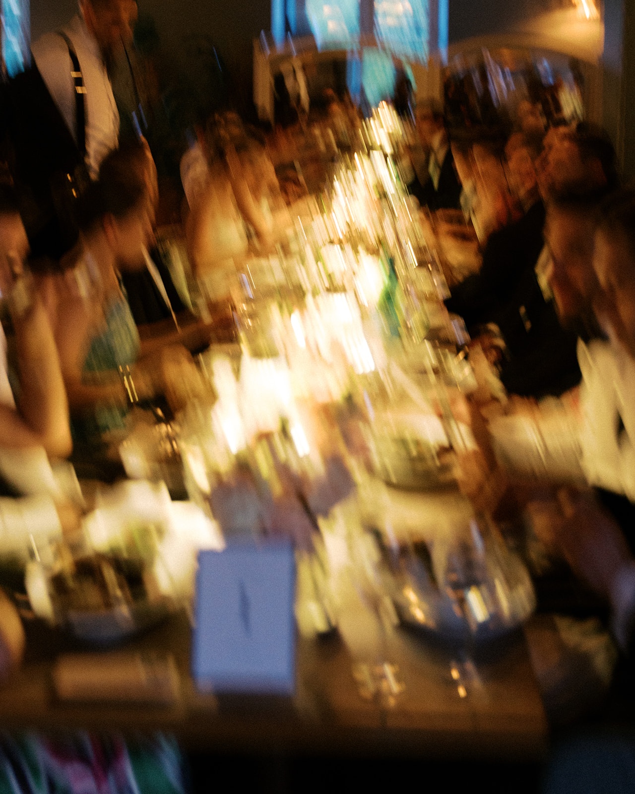 Motion-blurred long reception table with candles, florals, and seated guests at Restaurant l'Ile
