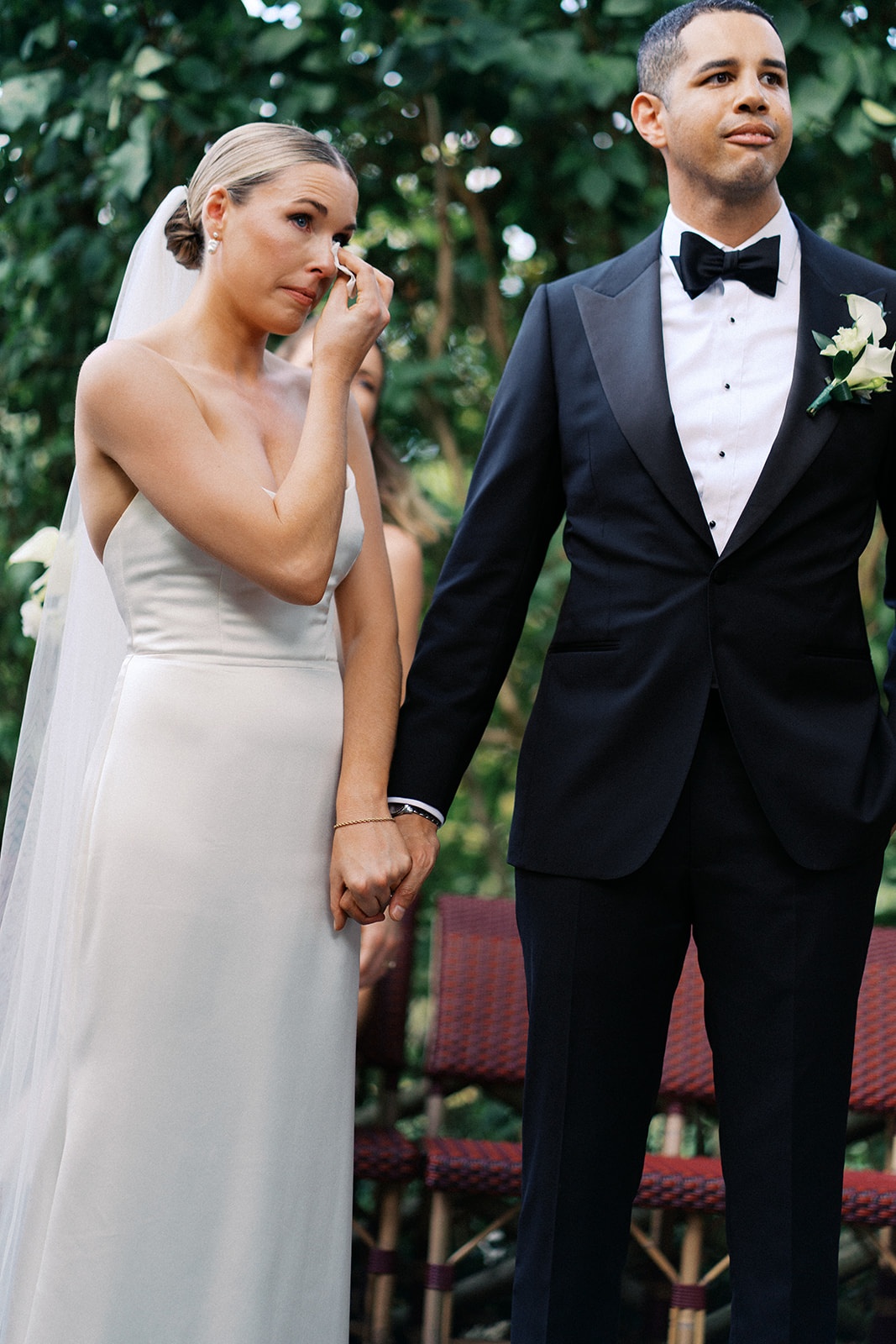 Tearful bride and composed groom hold hands at the outdoor altar at Restaurant l'Ile, Paris