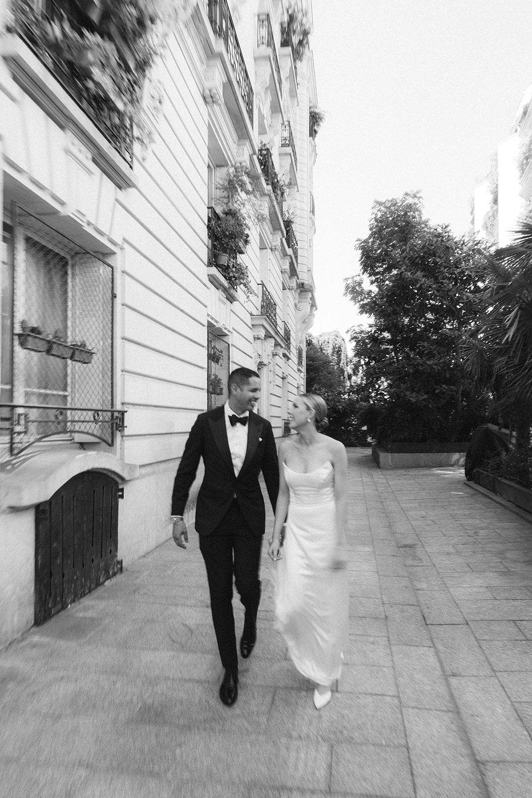 Black and white candid of the couple walking and laughing on a Paris street