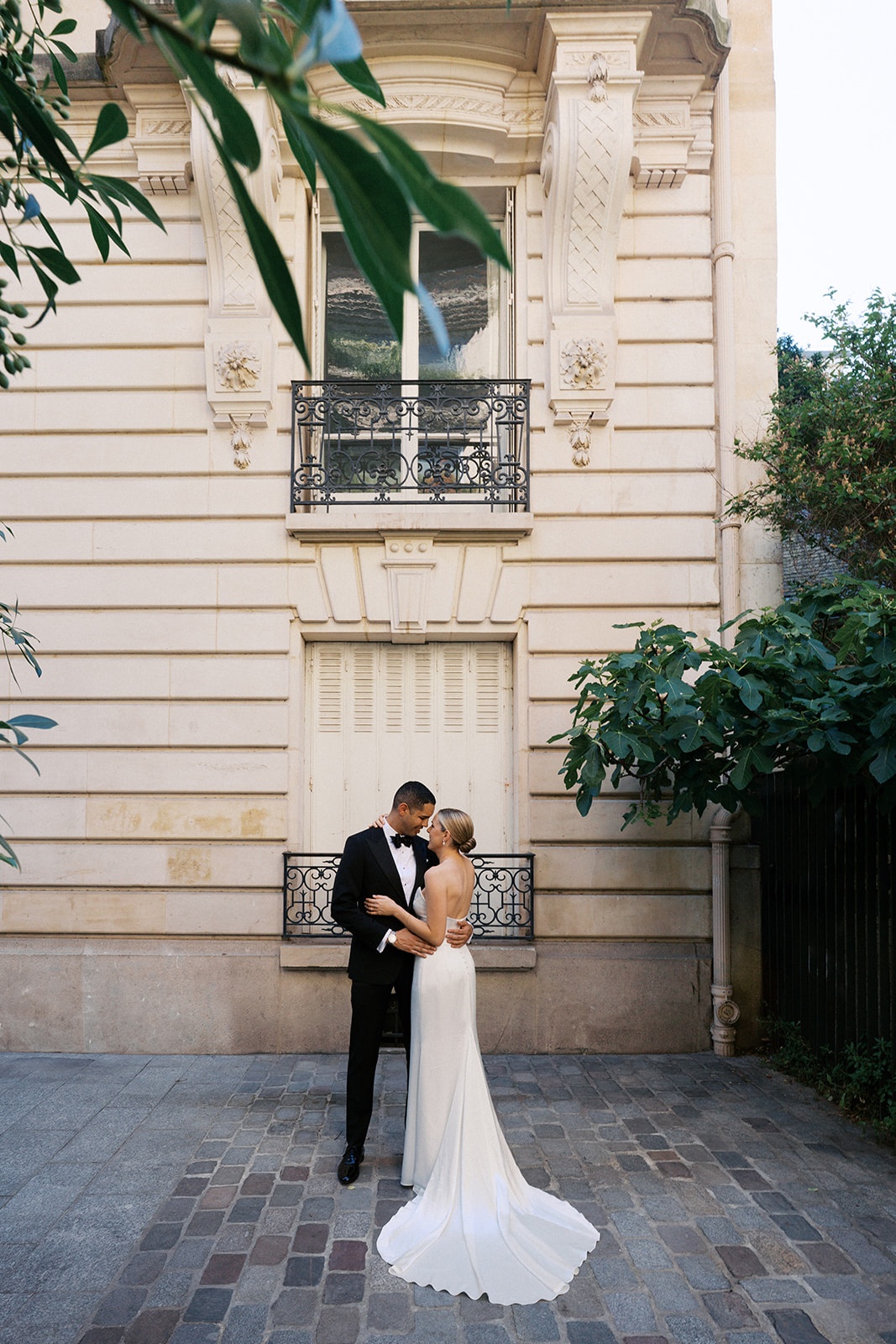 Couple embracing on a Paris cobblestone courtyard beneath a Haussmann facade