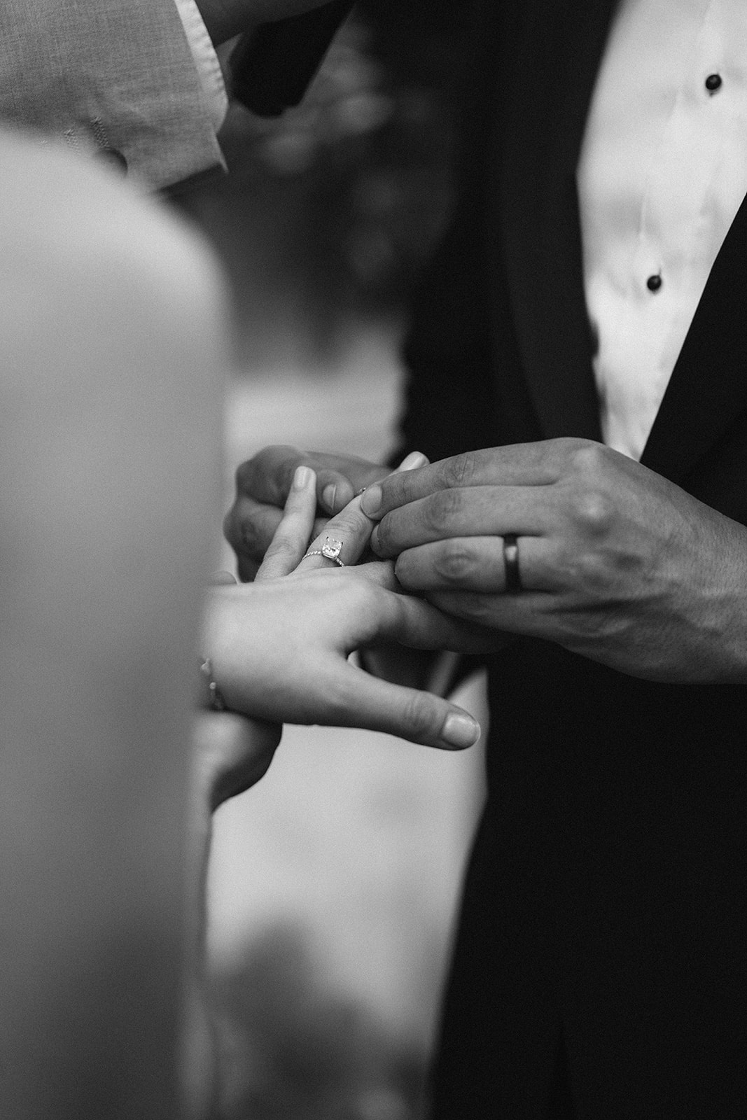Black and white close-up of the ring exchange at the altar at Restaurant l'Ile
