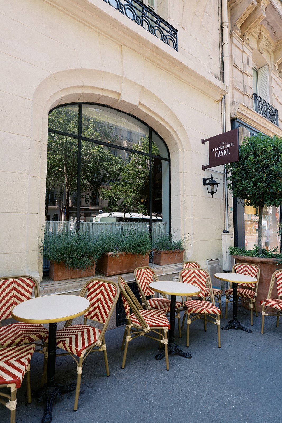 Red and white bistro chairs and round tables outside Le Grand Hotel Cayre in Paris