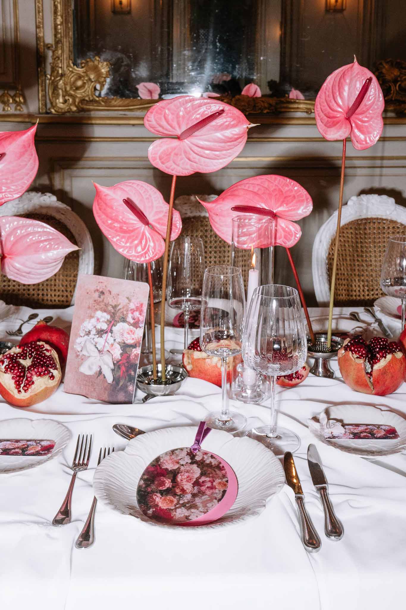 Pink anthurium centerpiece with pomegranate decor, floral fans, and scalloped chargers in gilded salon