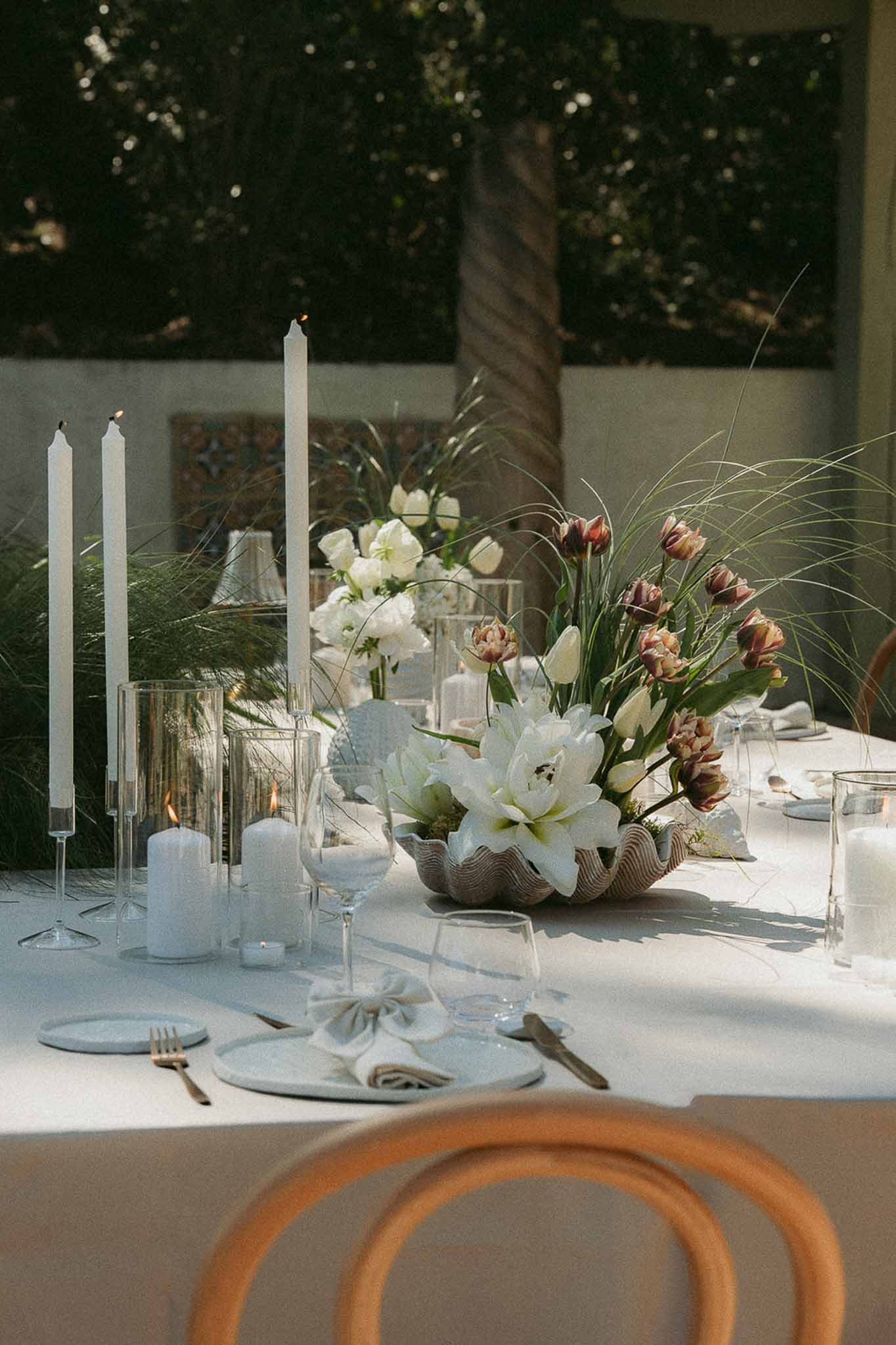 Reception table with blue-grey plates, gold flatware, taper candles, and white amaryllis centerpiece