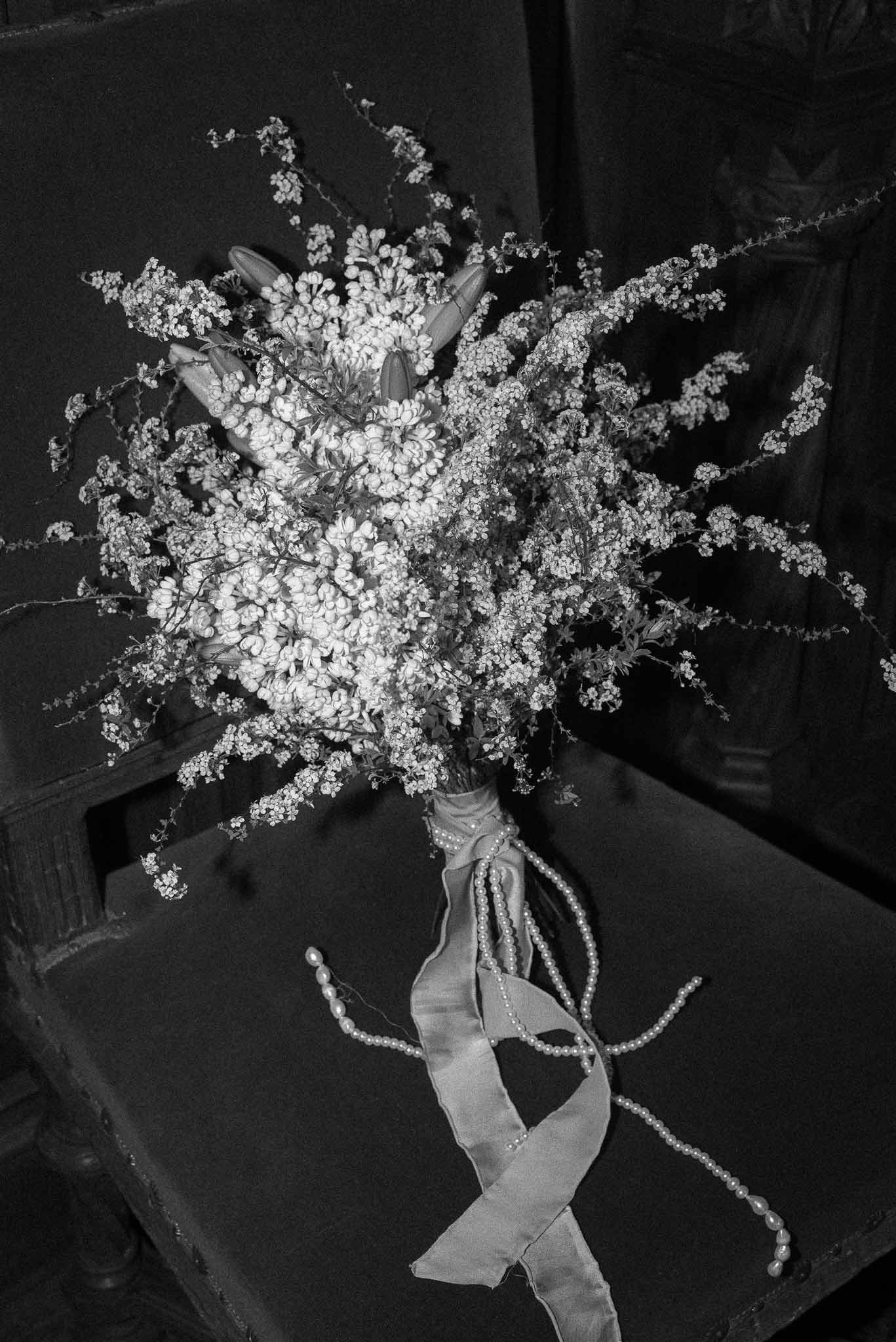 Black and white close-up of wild bouquet with gypsophila and tulips wrapped in satin ribbon and pearls