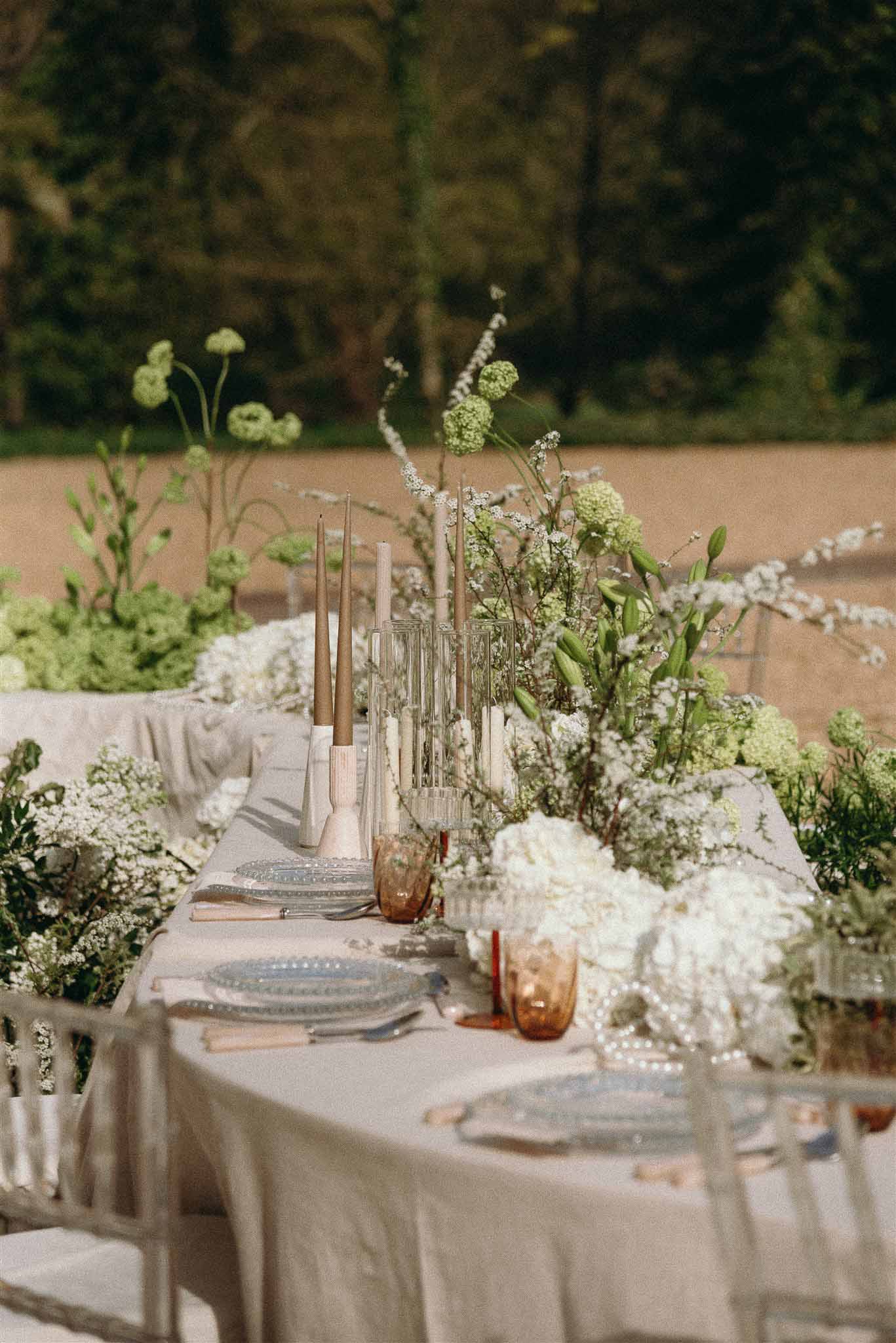 Reception table with blue hobnail charger plates, gypsophila runner, and beige taper candles