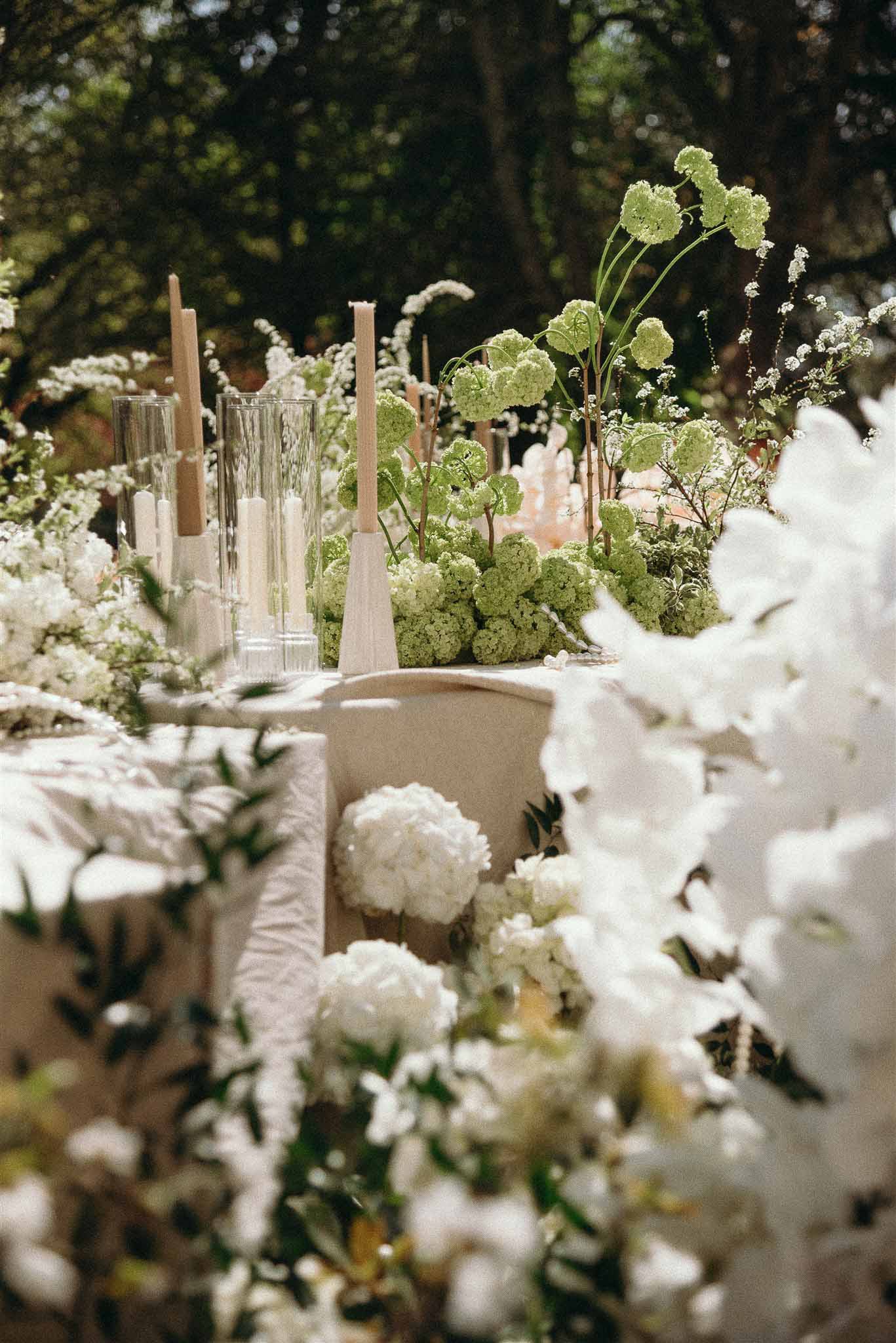 Garden reception table with white peony and orchid centerpiece and ivory taper candles