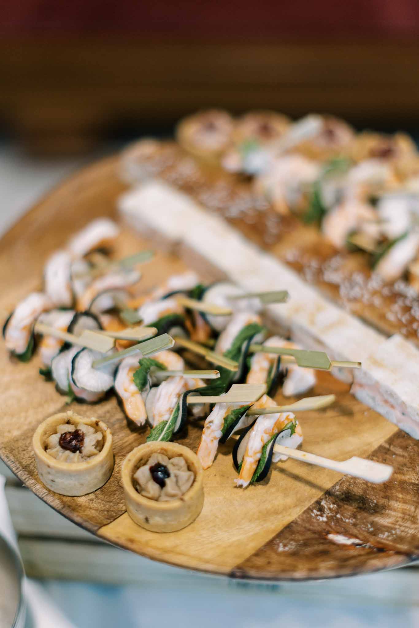 Prawn and courgette skewers with tartlets arranged on rustic wooden serving board