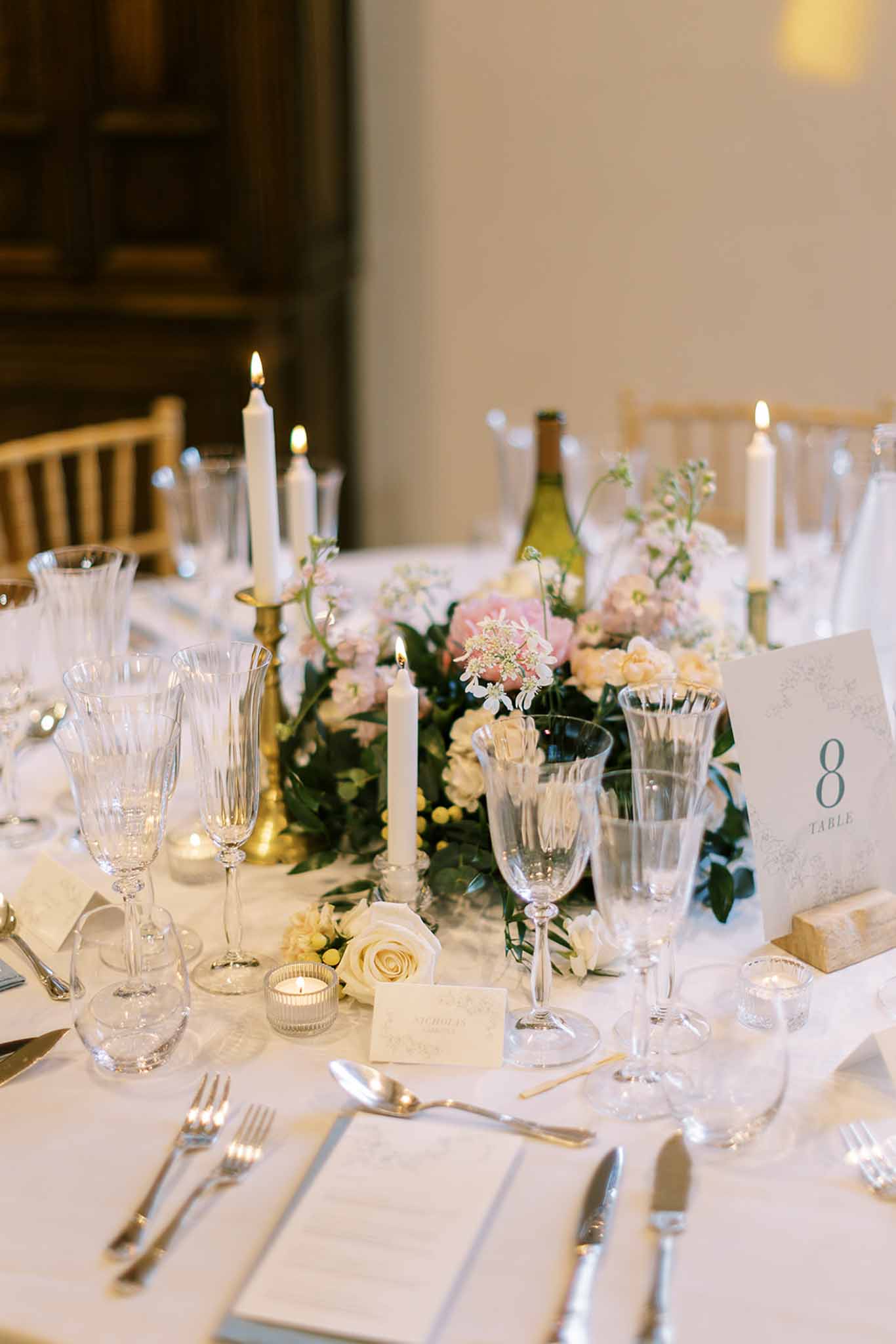 Reception table with blush peony and ivory rose centerpiece, brass candlesticks, and crystal glassware at table 8