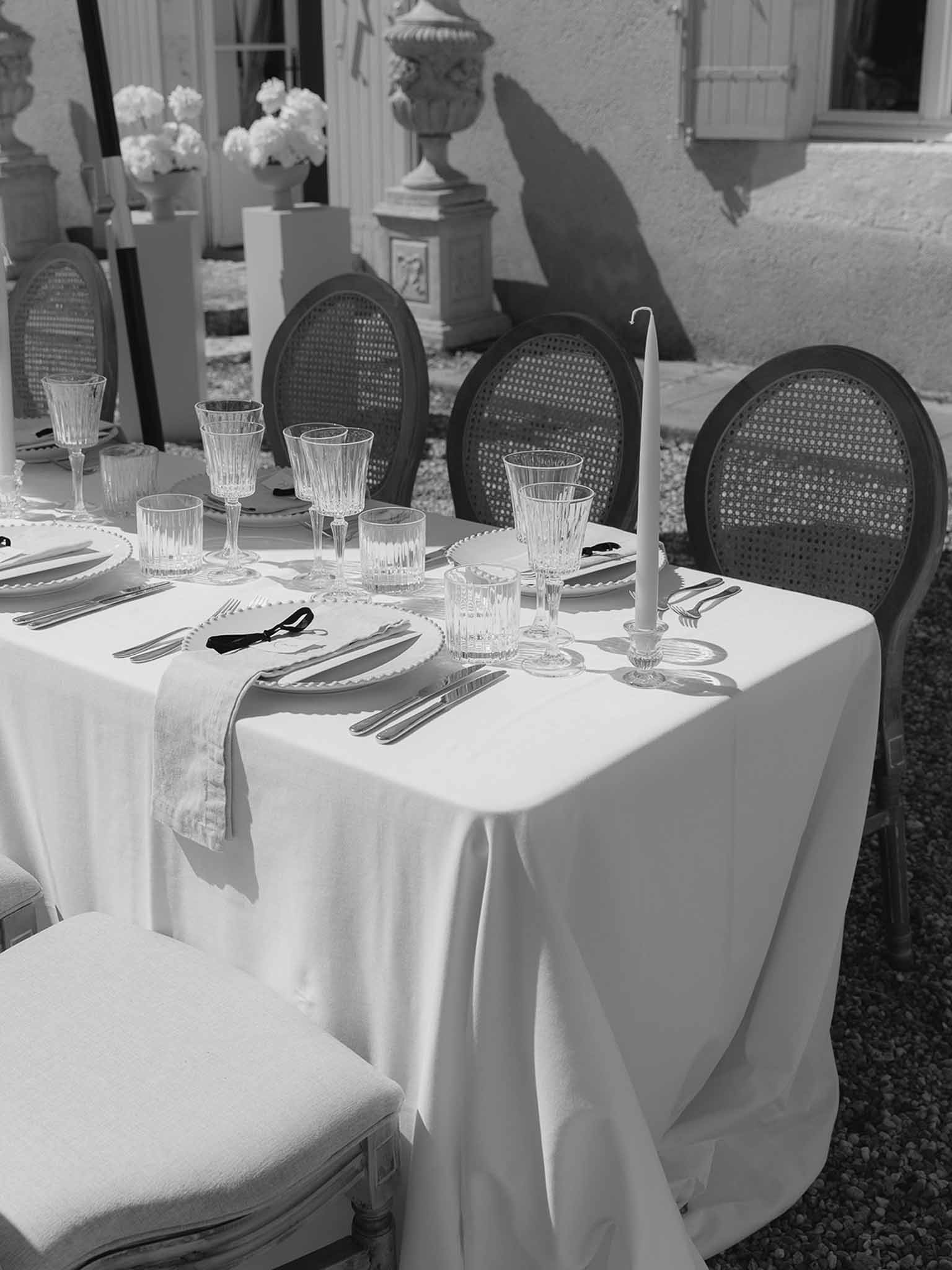 Black and white reception table with scallop charger plates, crystal glasses, and cane-back chairs