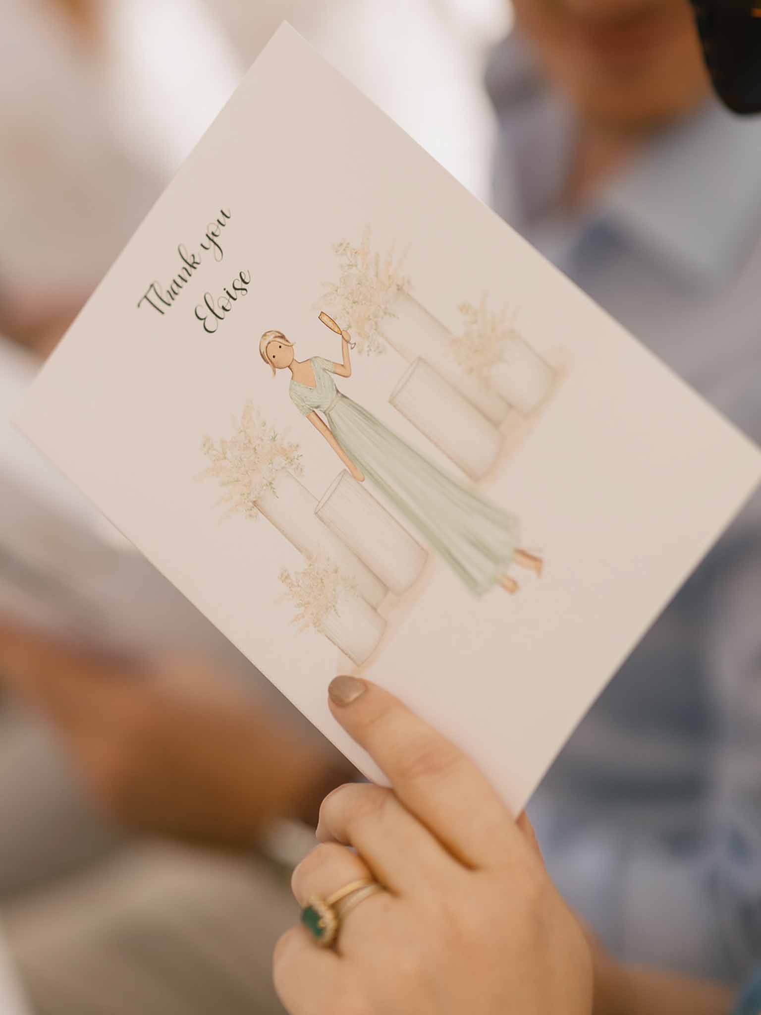 Hand holding personalized watercolor thank-you card with sage green dress illustration and calligraphy