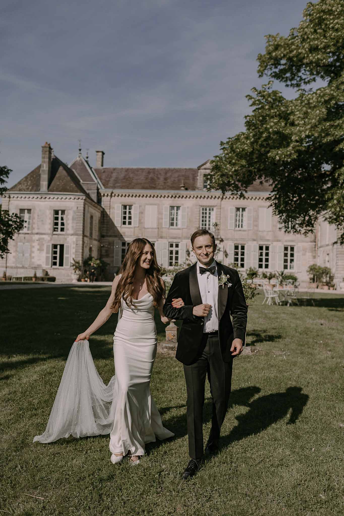 Bride and groom walking hand in hand in a garden