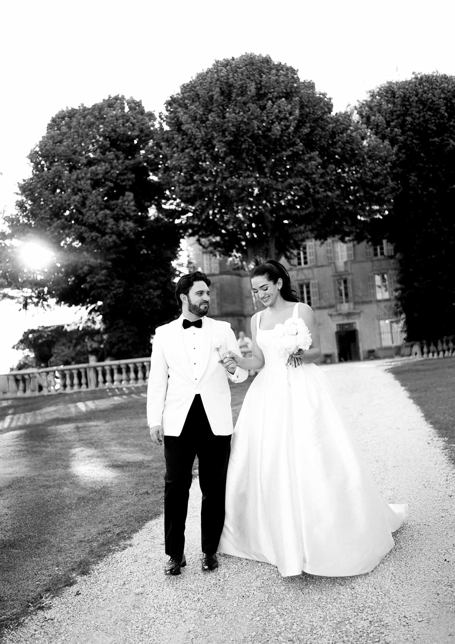 Black and white photo of bride and groom walking hand in hand
