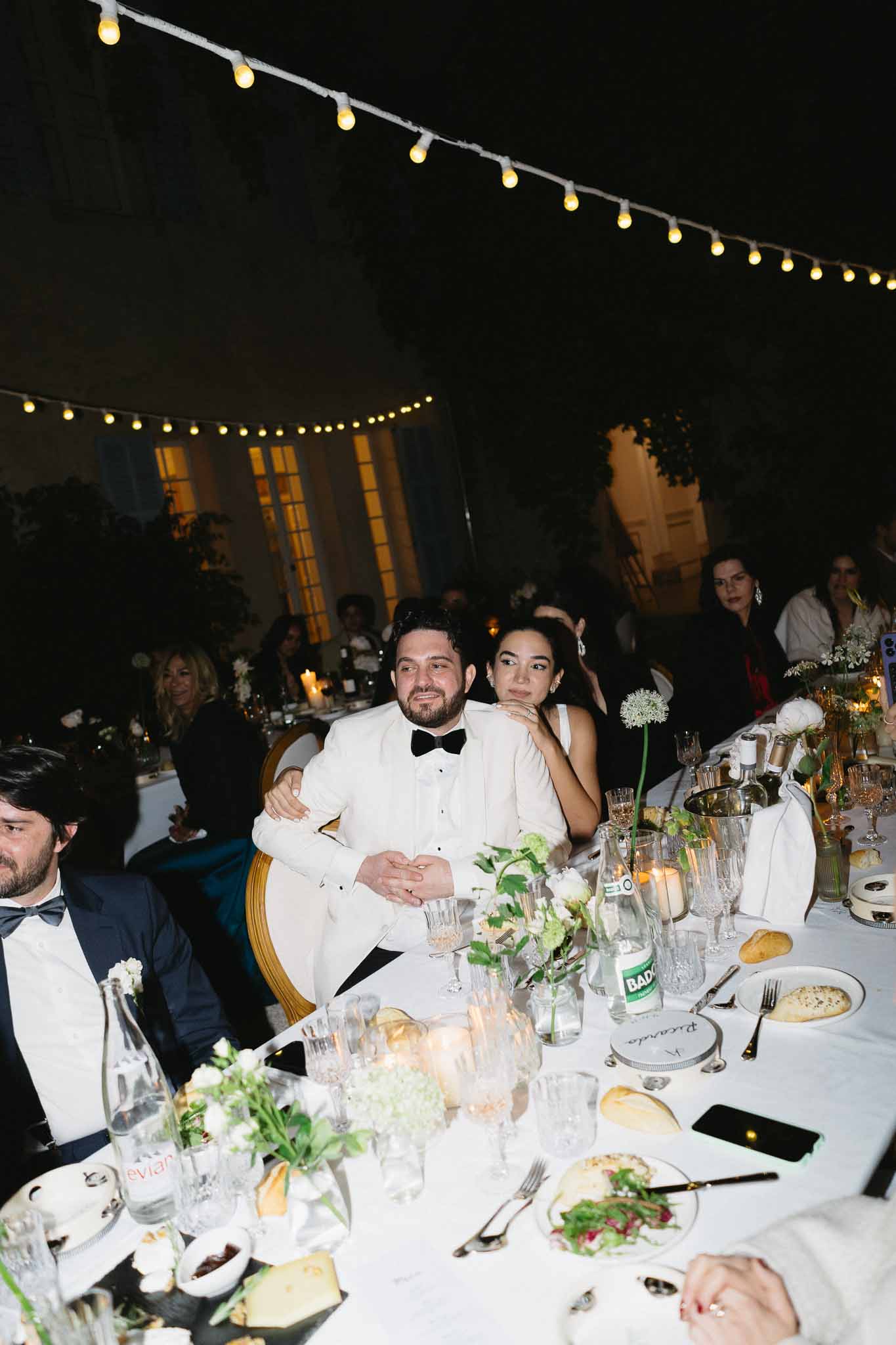 Black and white photo of wedding reception table setting in a garden with white roses
