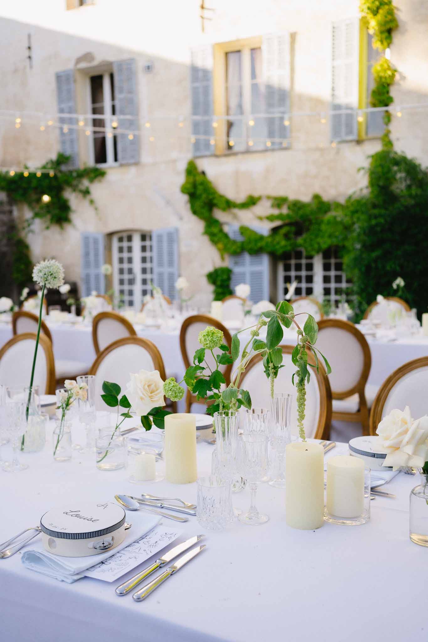 Round table with cream roses and viburnum bud vases, navy plates, and gold chairs at stone manor