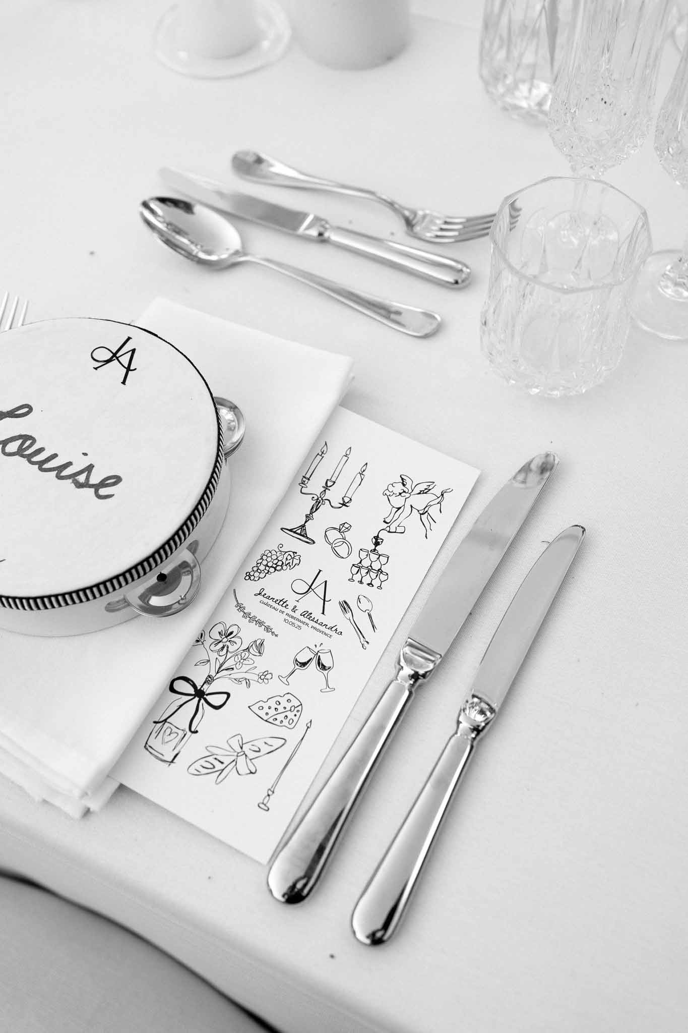 Black and white illustrated menu card and tambourine place card with silver cutlery and crystal glasses