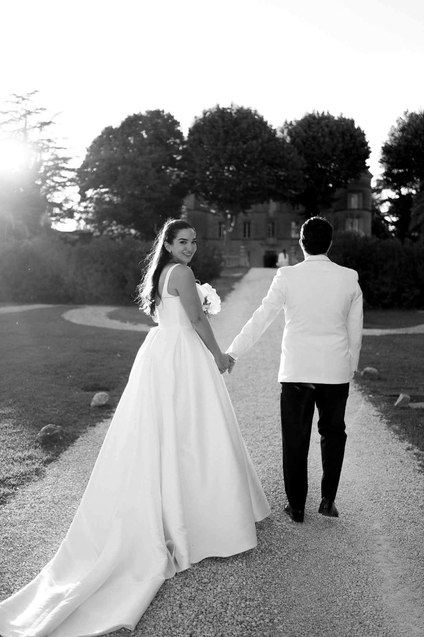 Black and white photo of bride and groom walking hand in hand