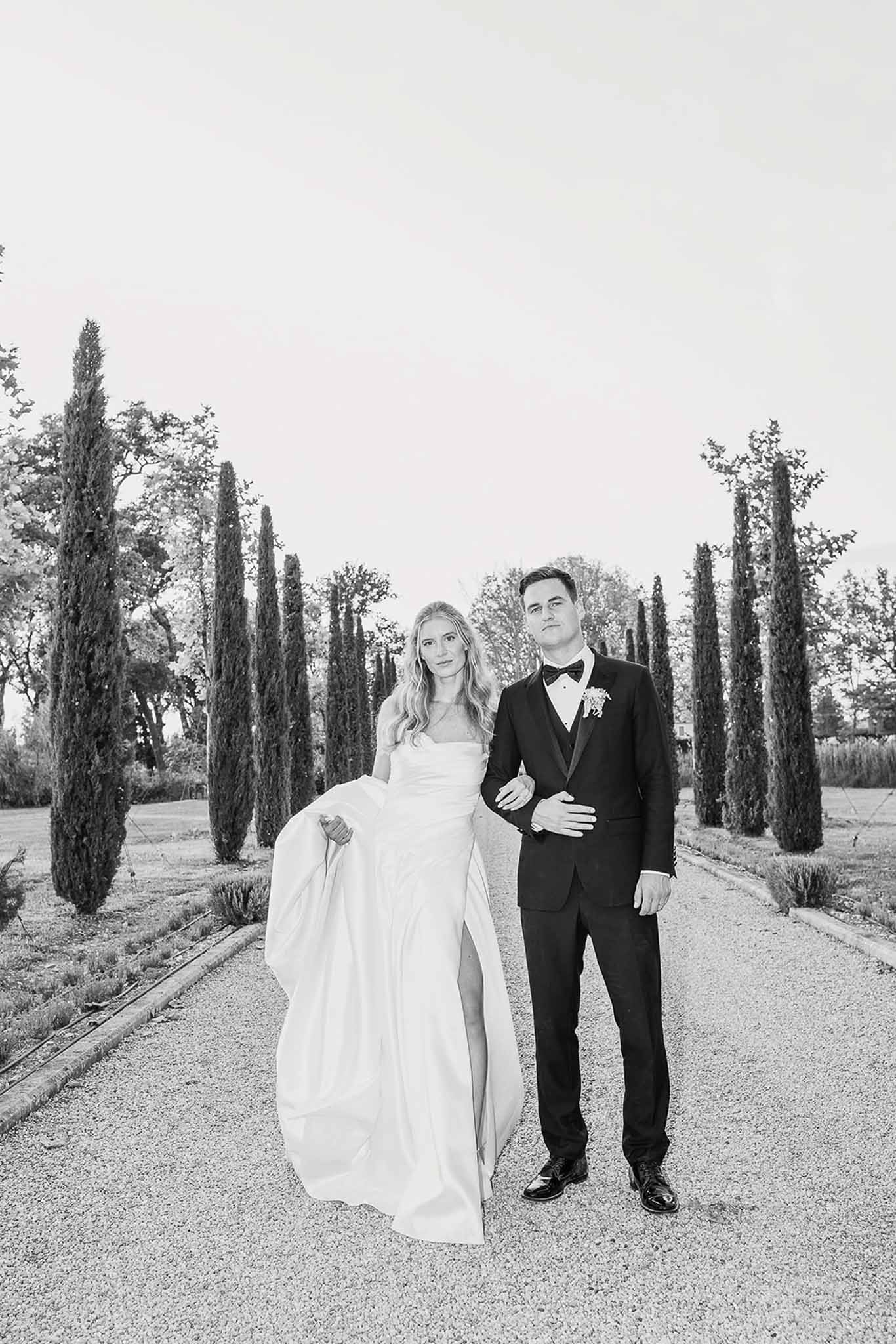 Black and white couple portrait on cypress-lined allee with bride in strapless ballgown and groom in tuxedo