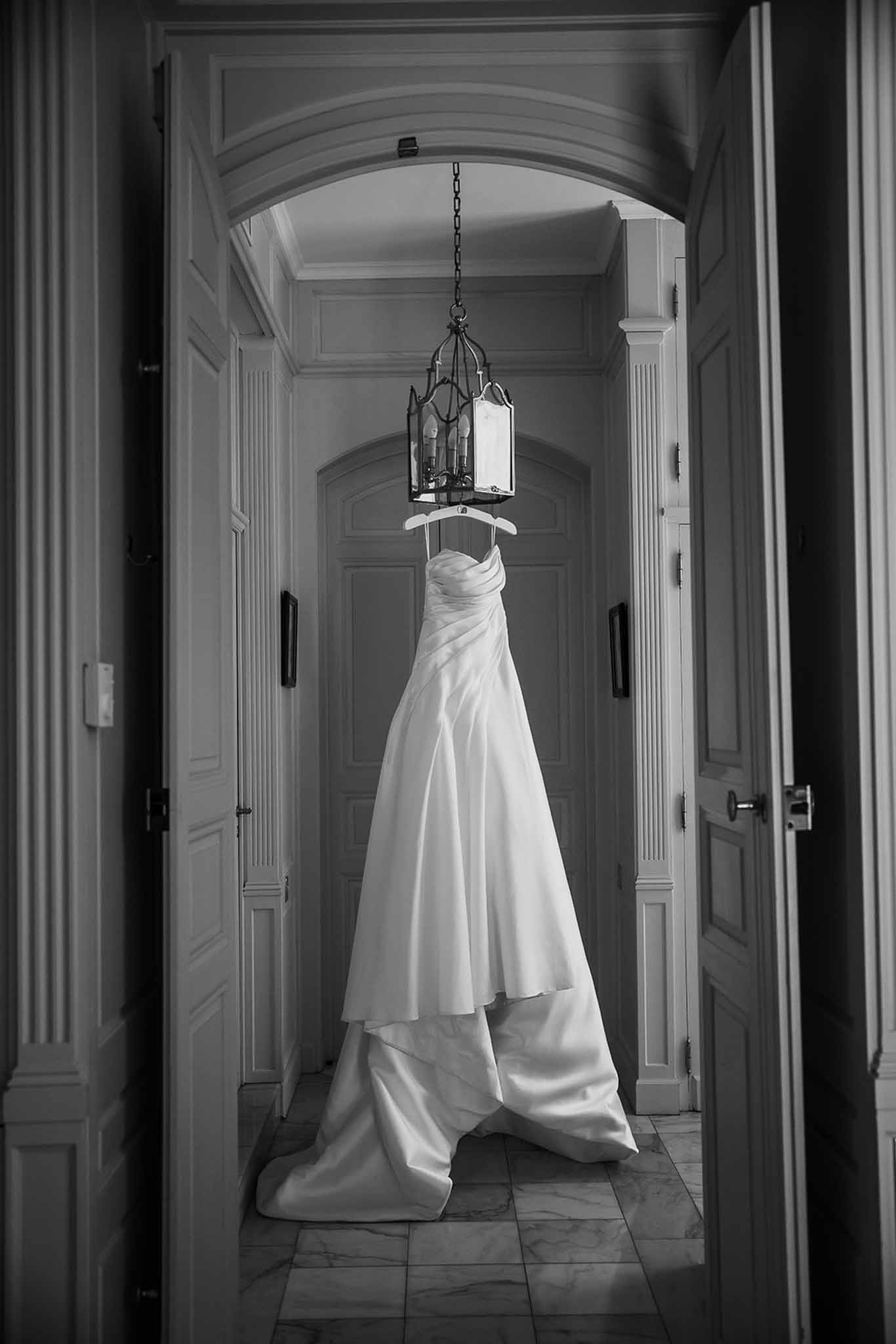 Black and white strapless satin gown hanging from iron lantern in panelled chateau hallway