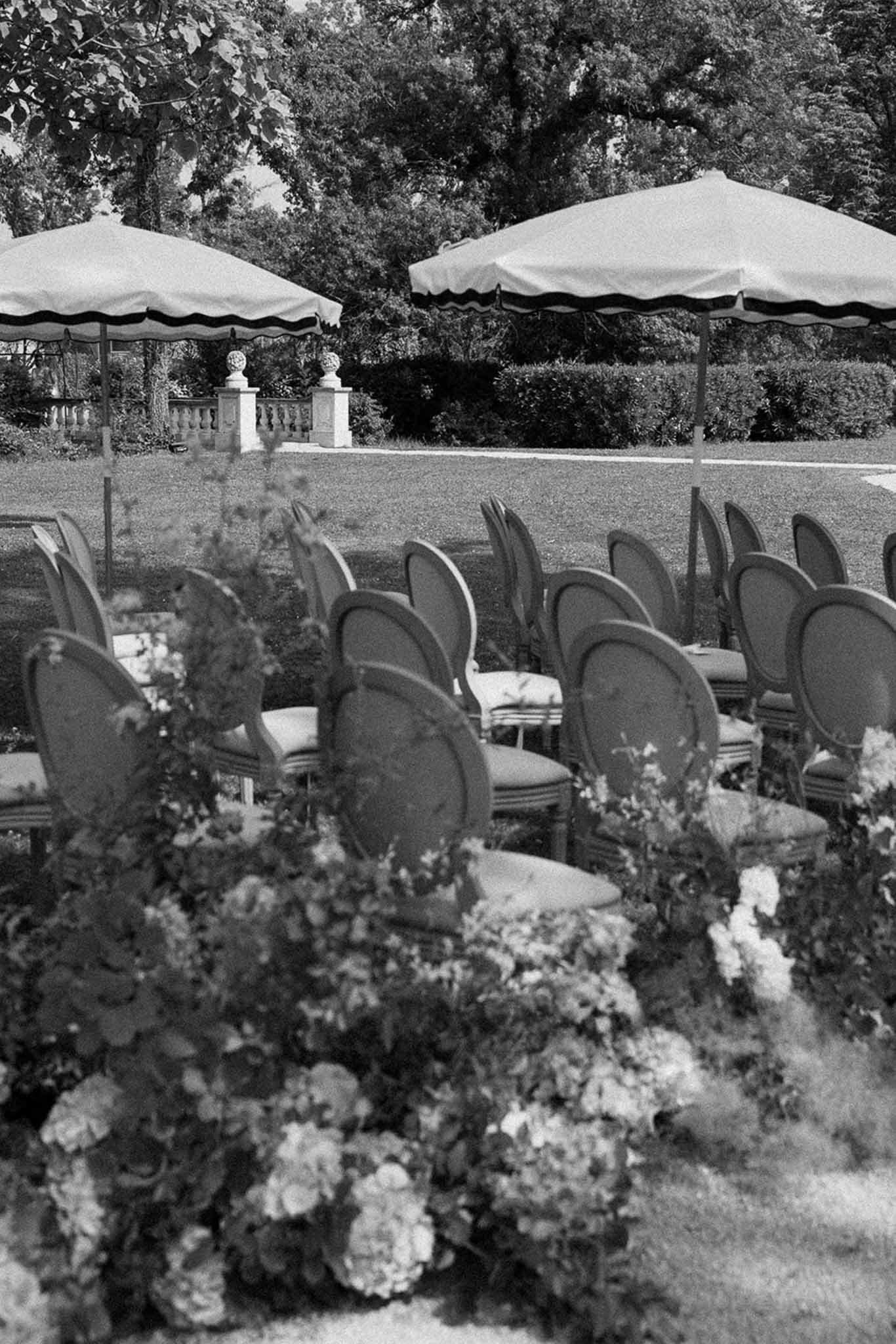 Black and white pre-ceremony setup with medallion chairs, aisle hydrangeas, and scalloped umbrellas