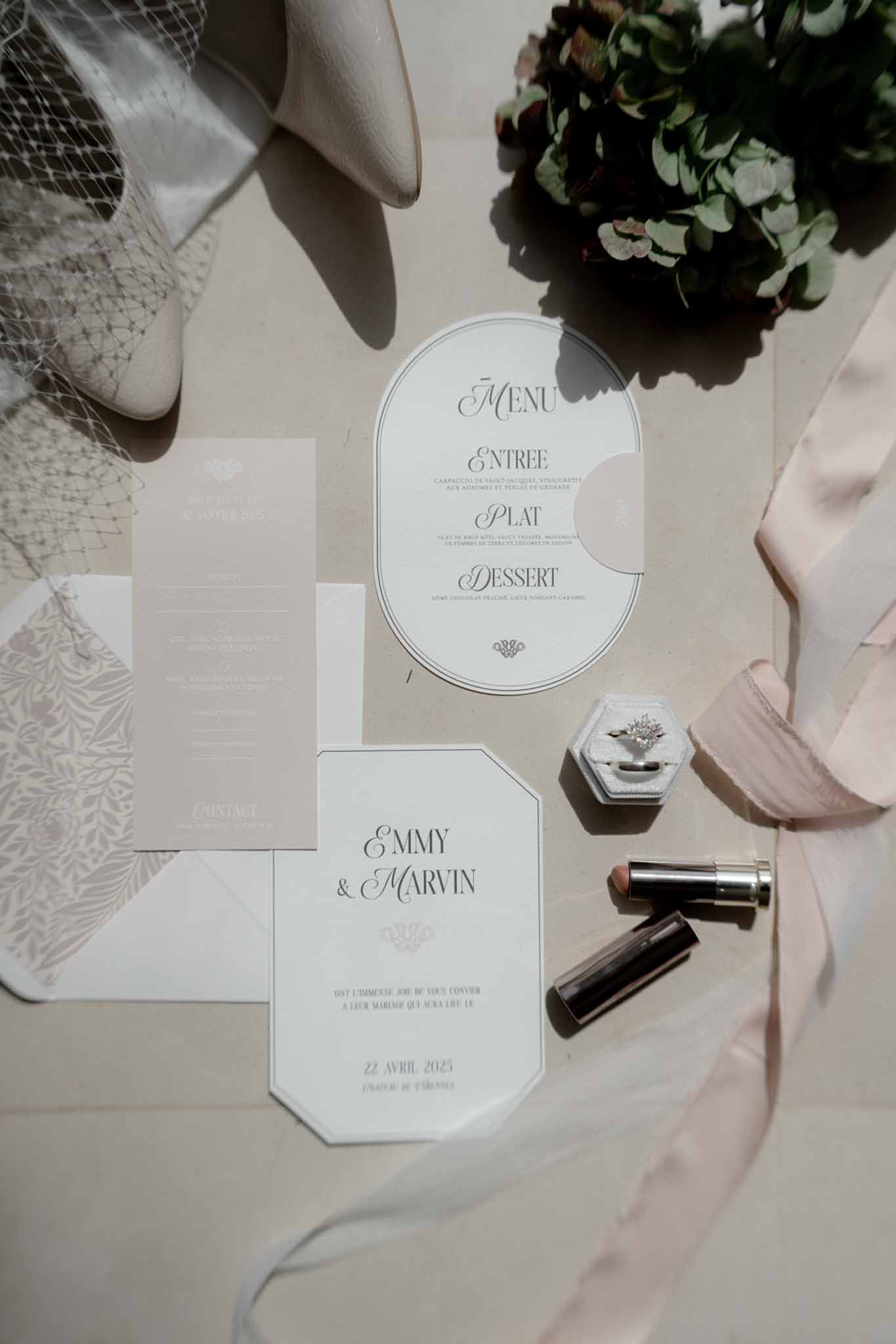 Stationery flat lay with octagonal invitation ring box ivory heels and birdcage veil on linen