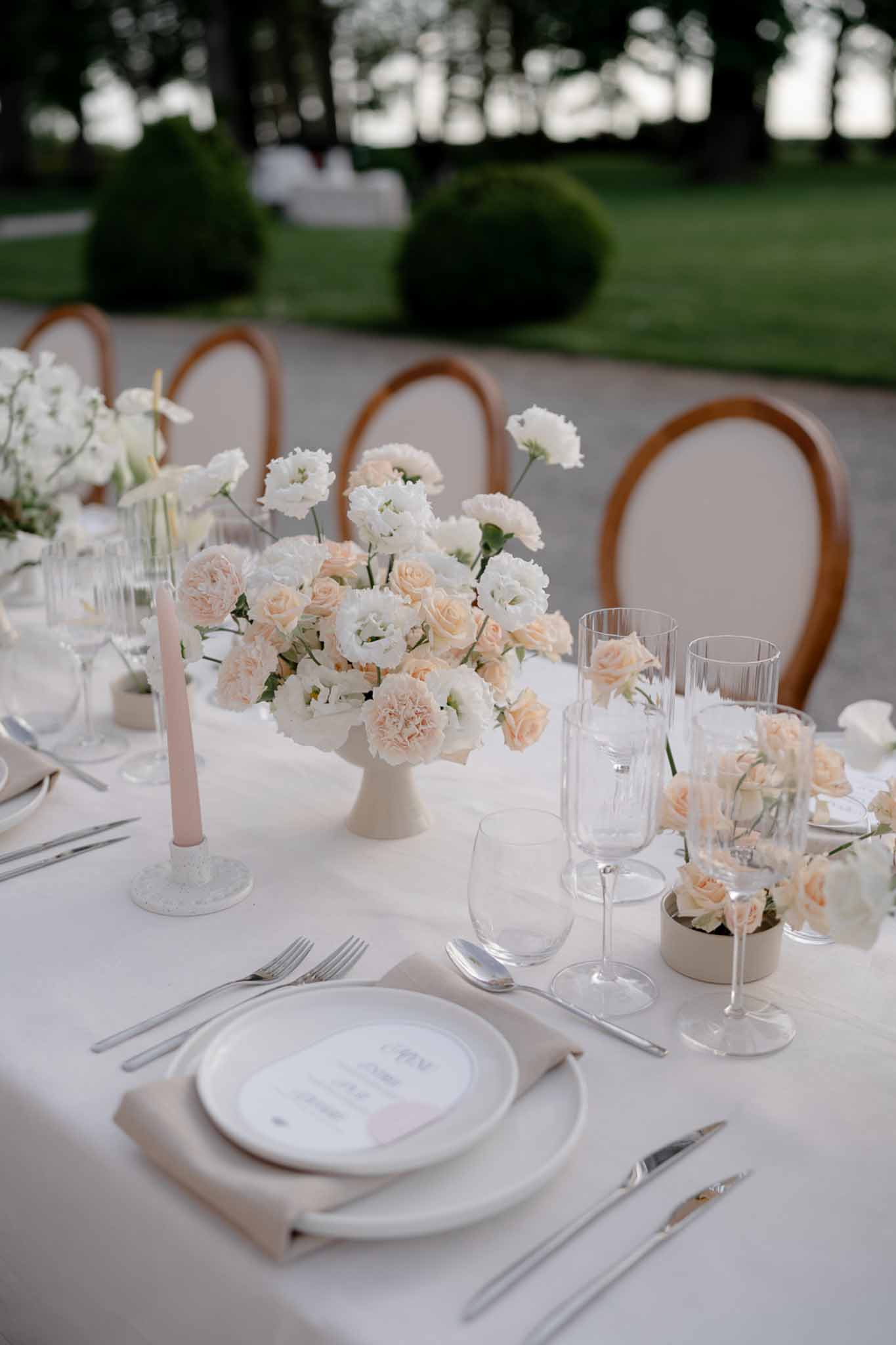 Garden table with blush and peach rose compote centerpiece beige vessels printed menus and bentwood chairs
