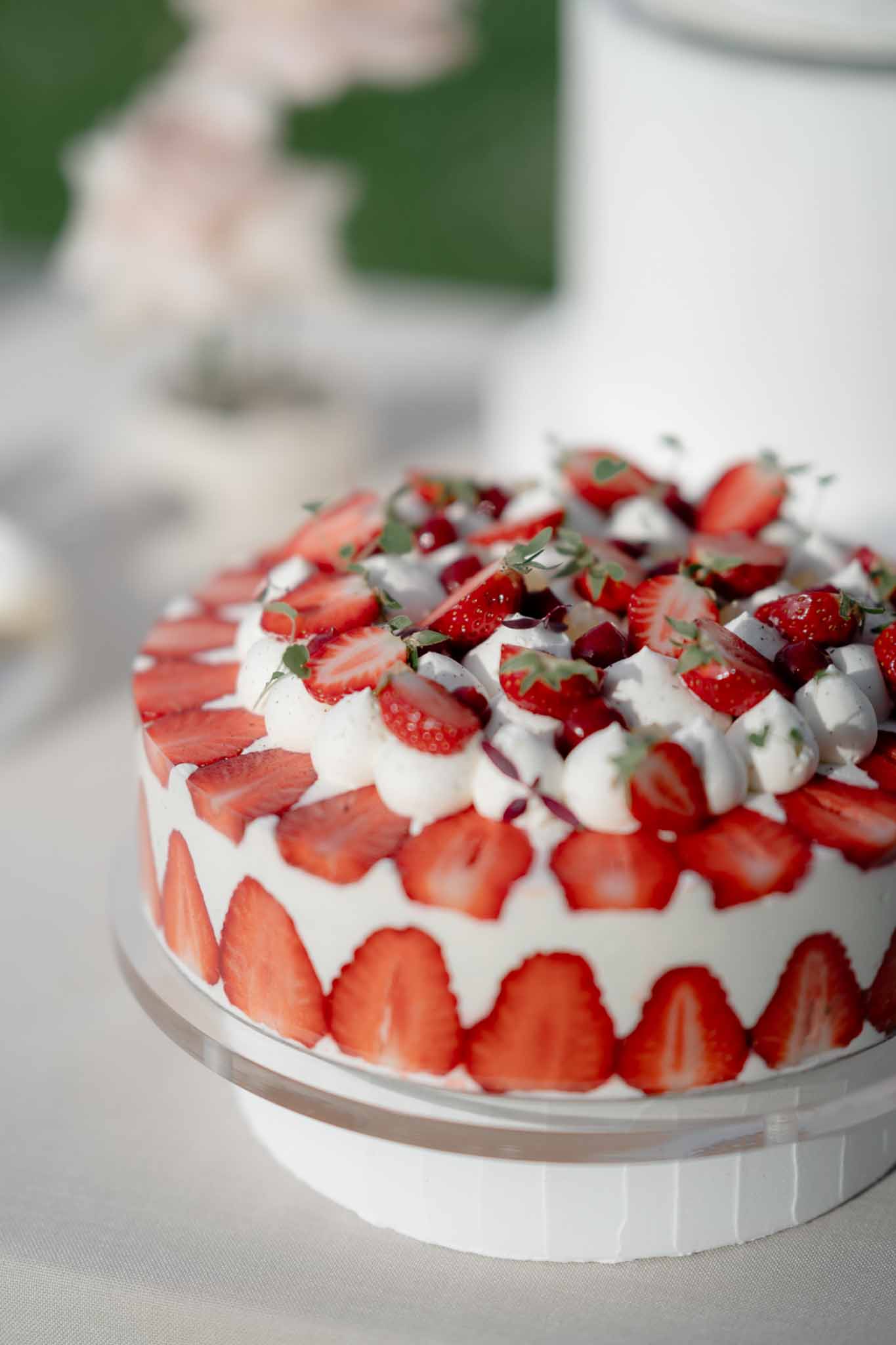Single-tier white cake decorated with sliced fresh strawberries, piped rosettes, and pomegranate seeds