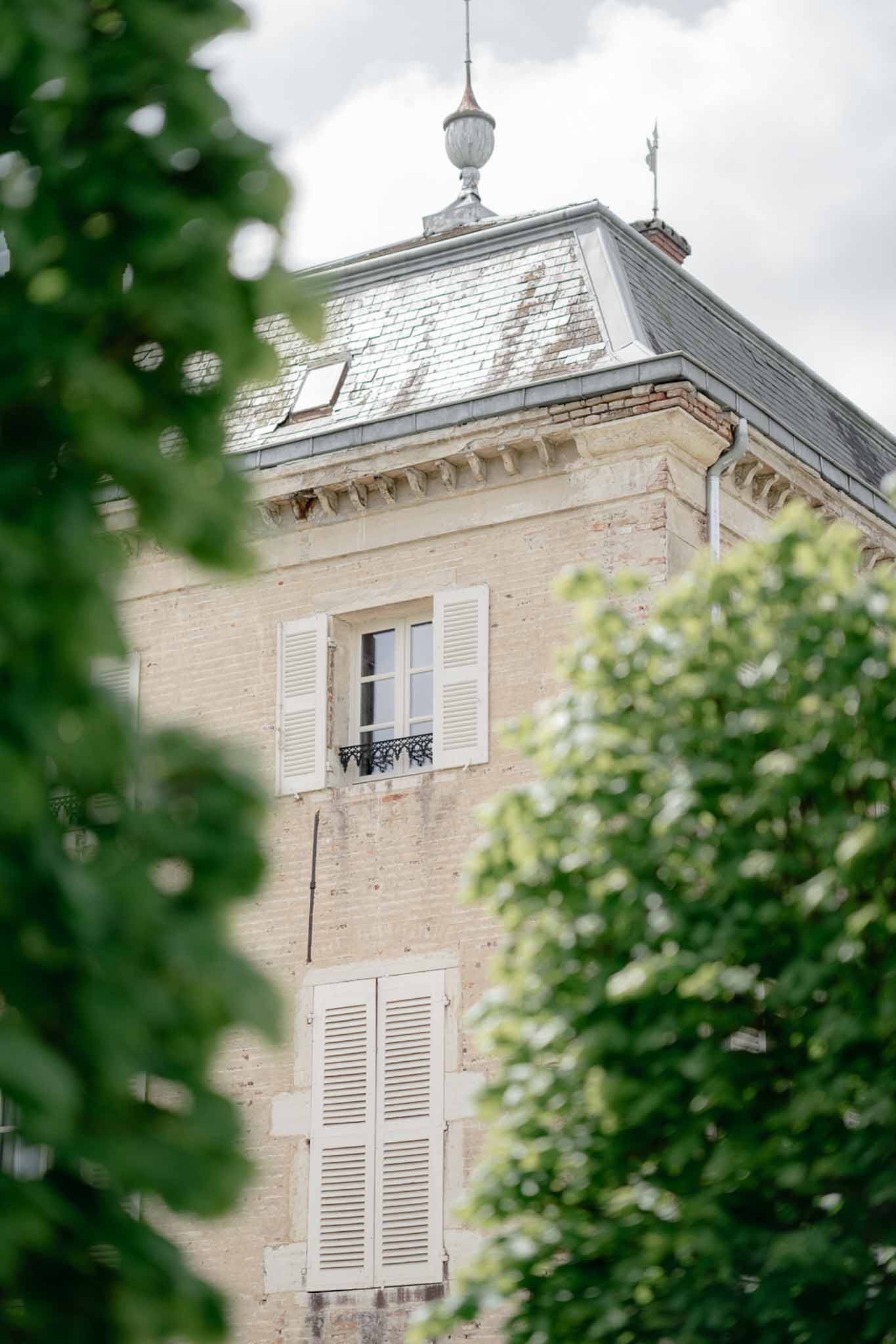 Chateau tower with cream stone louvered shutters wrought-iron balcony and slate mansard roof