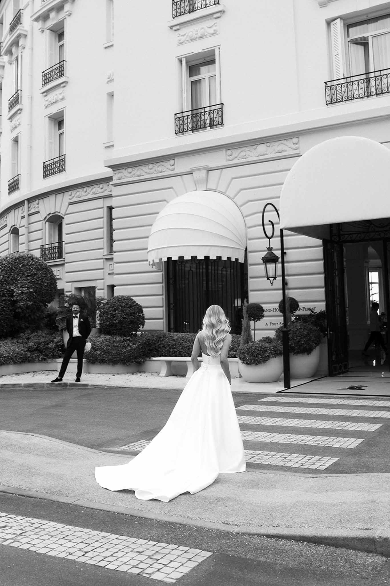Black and white bride in ball gown with cathedral train facing groom at Grand-Hotel du Cap-Ferrat entrance