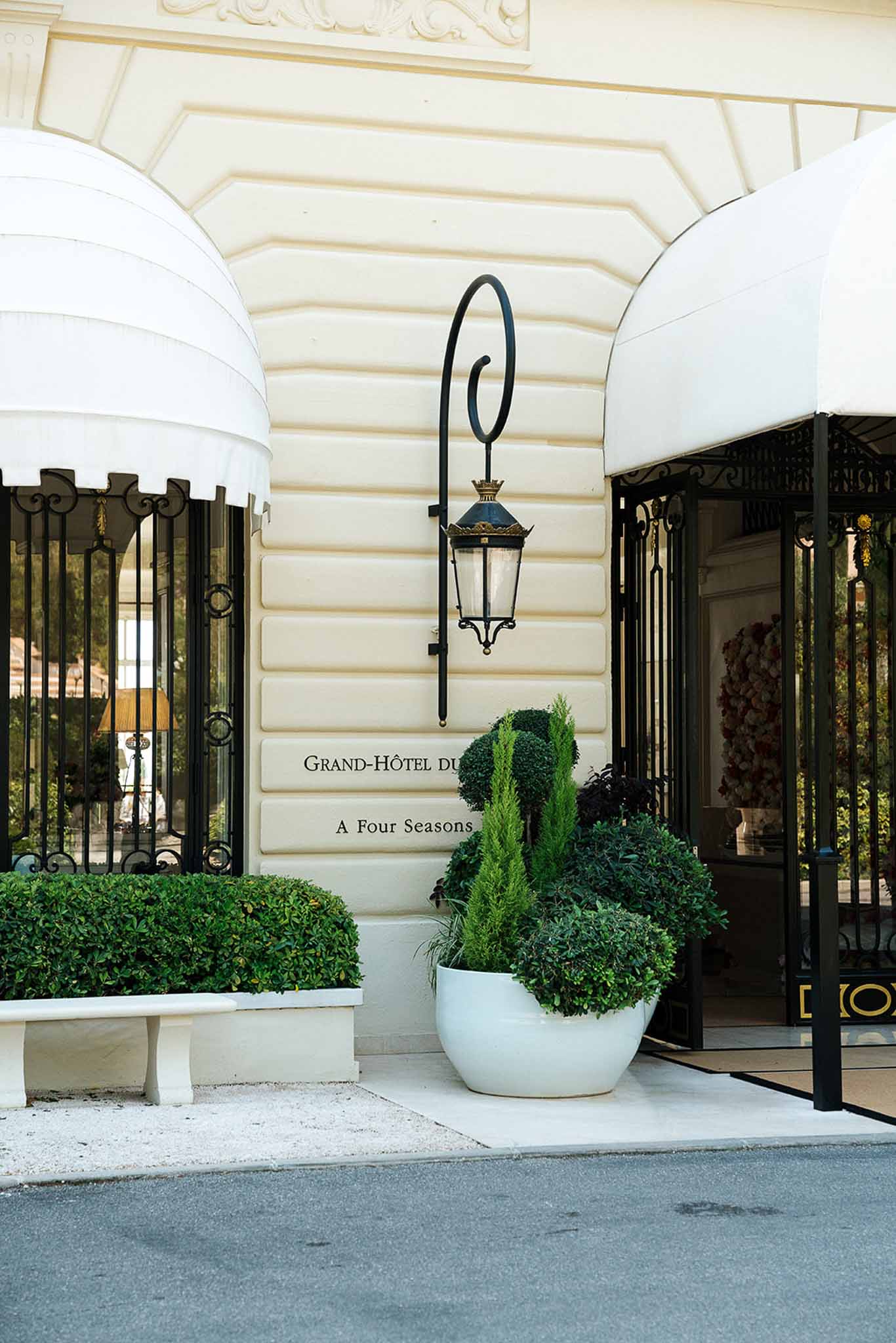 Grand Hotel du Cap-Ferrat Beaux-Arts entrance with wrought-iron gates, striped awnings, and boxwood hedges