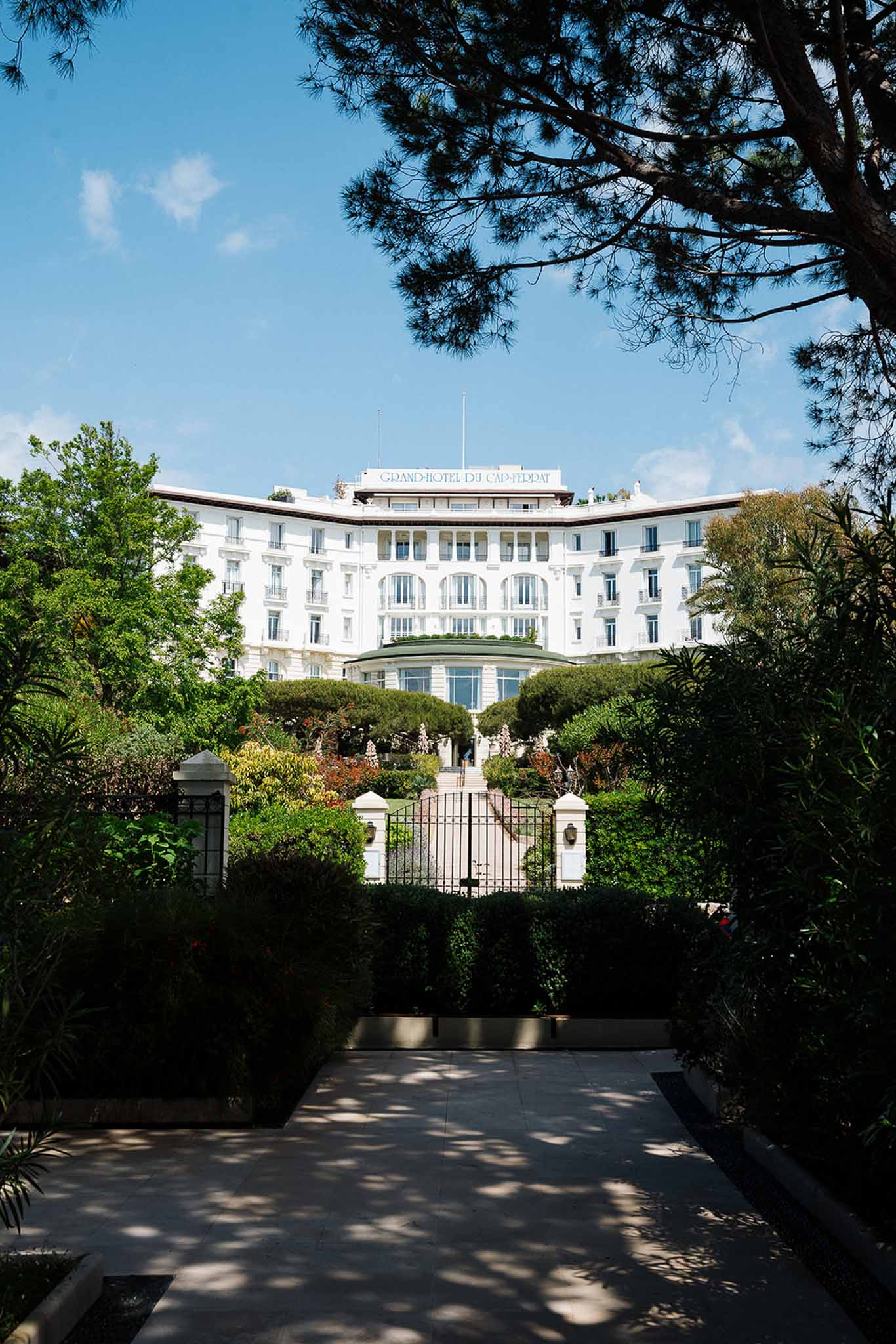 Grand-Hotel du Cap-Ferrat white Belle Epoque facade viewed through iron gates and manicured gardens