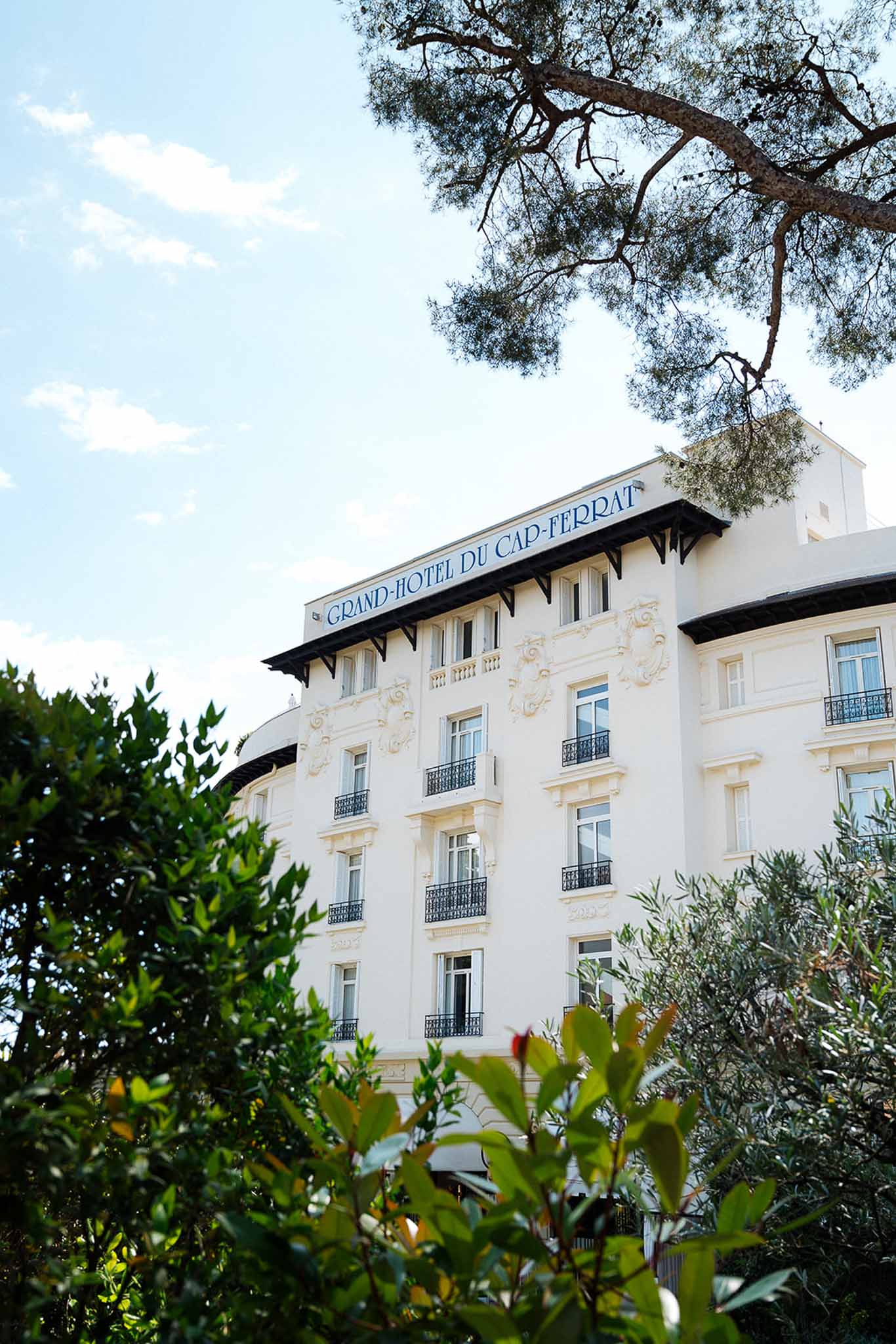 White Belle Epoque facade of Grand-Hotel du Cap-Ferrat with wrought-iron balconies and blue signage