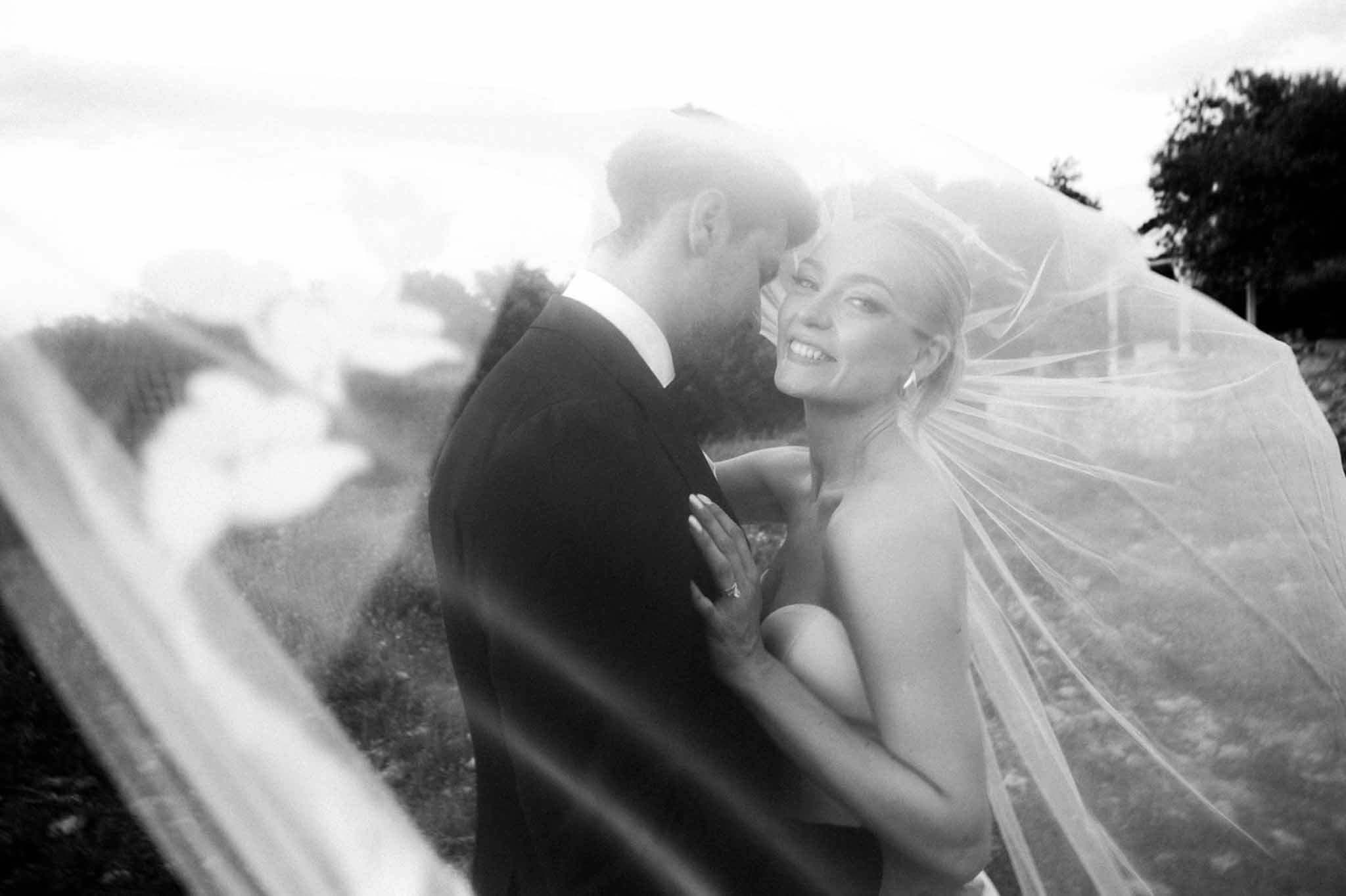 Black and white couple smiling through billowing veil creating hazy layered overlay effect