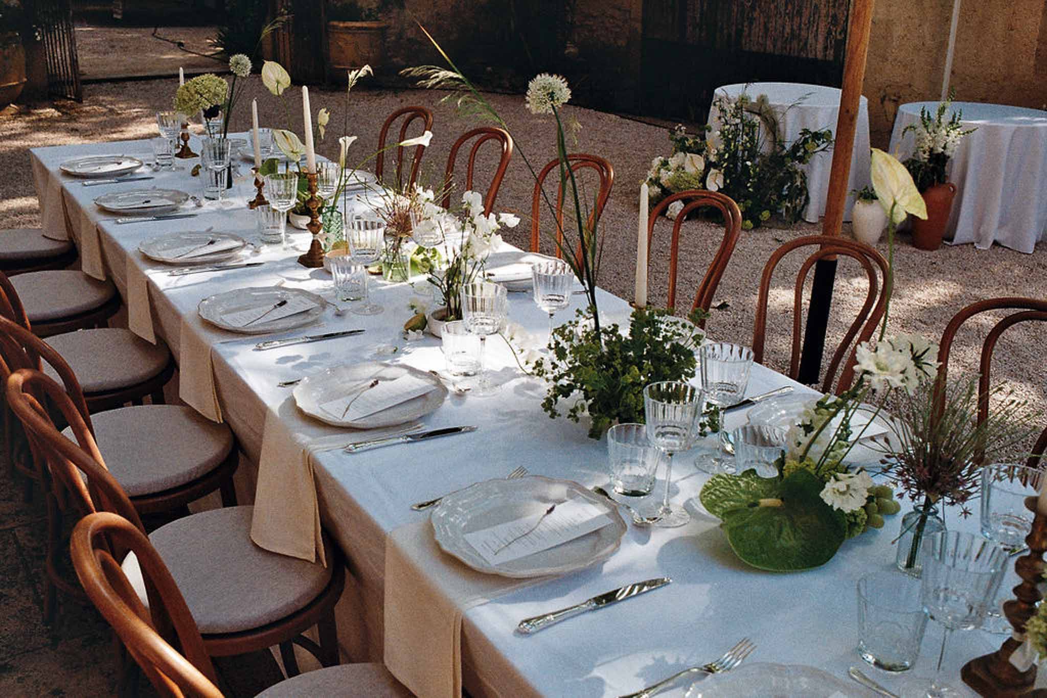 Garden-style table with white sweet pea and allium centerpieces, brass candles, and cabbage-leaf charger