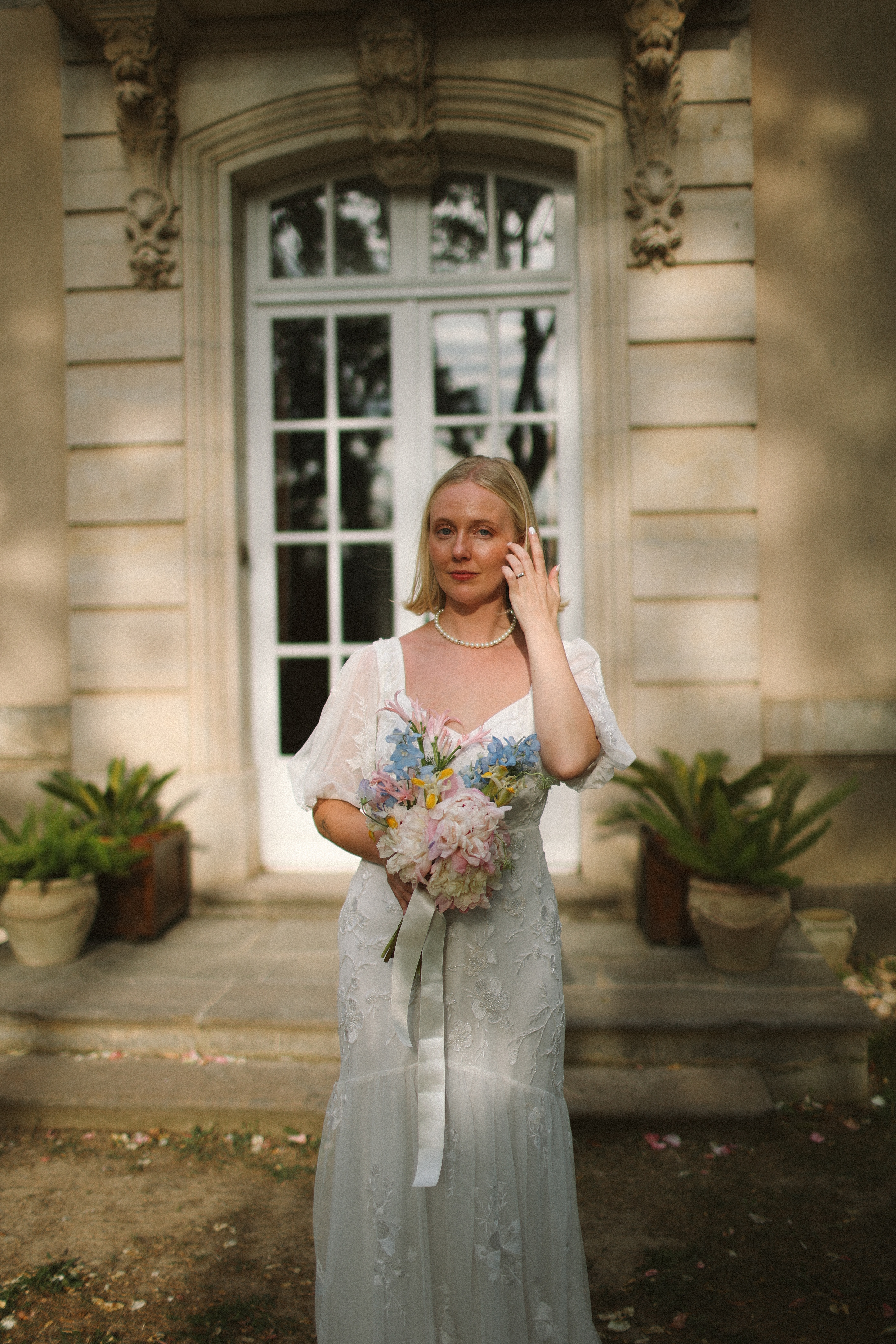 Bride holding pastel bouquet in front of chateau entrance at Chateau du Puits es Pratx, Ginestas