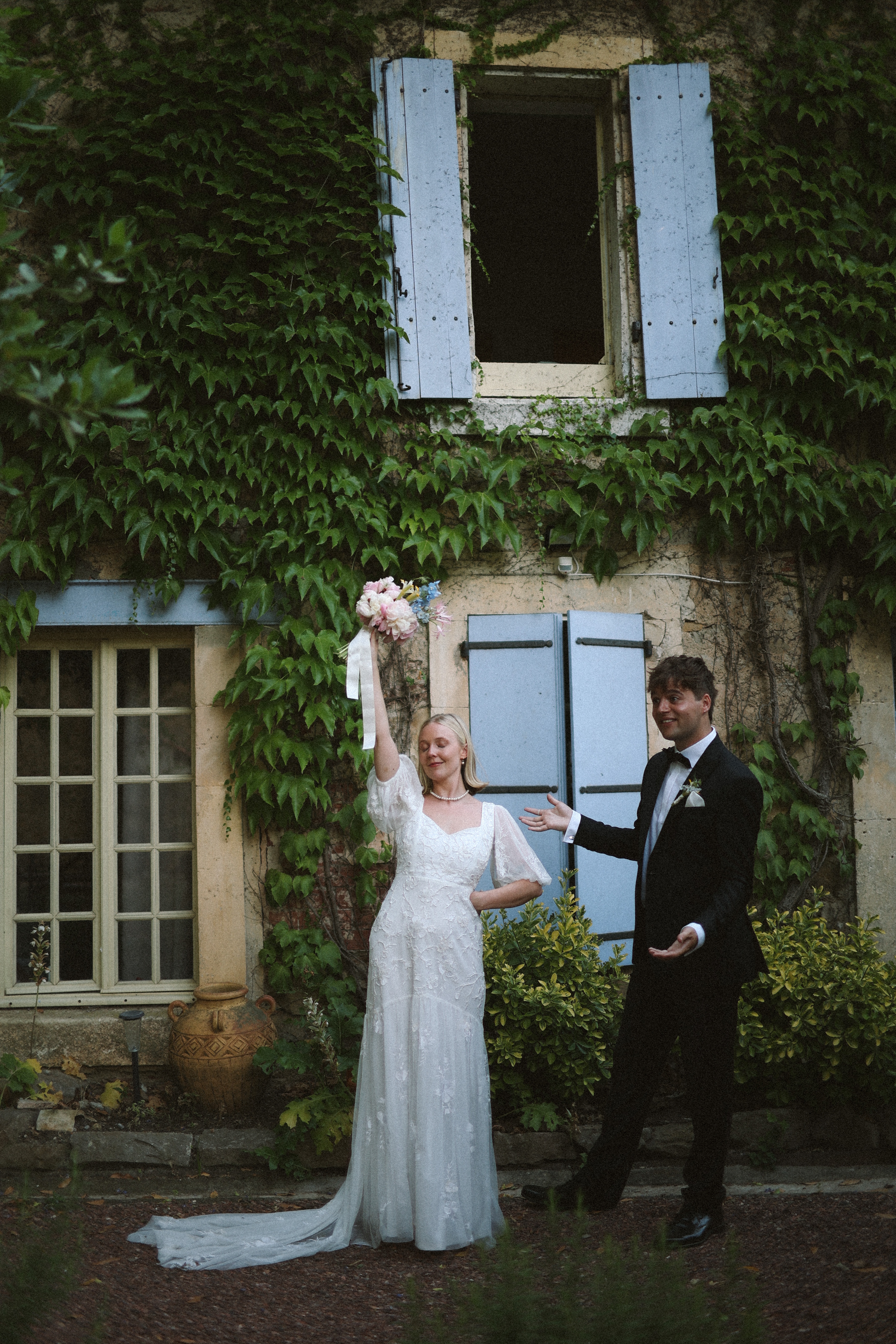 Couple by ivy covered shuttered wall at Chateau du Puits es Pratx, Ginestas