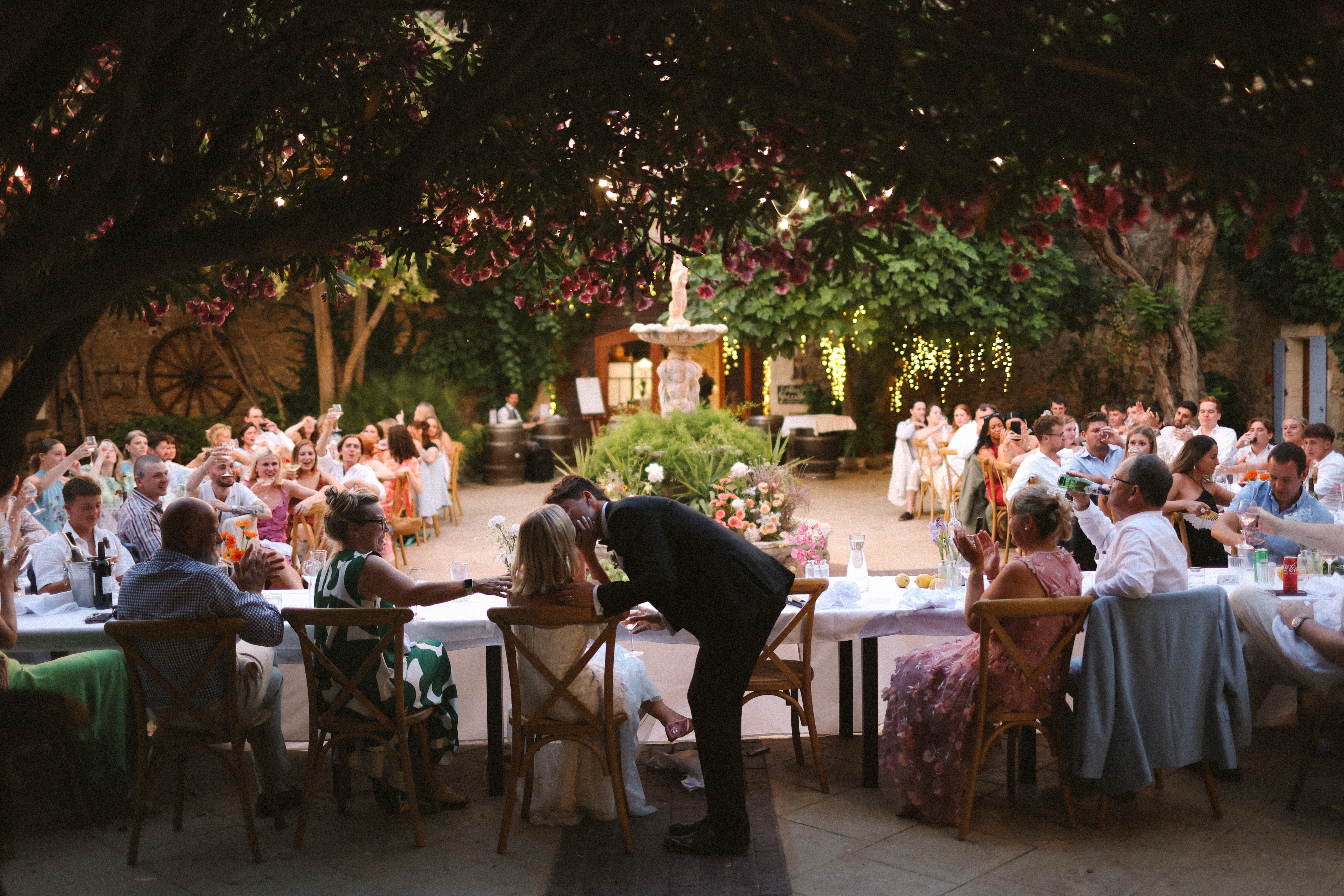 Guests toasting as couple kiss at dinner table at Chateau du Puits es Pratx, Ginestas