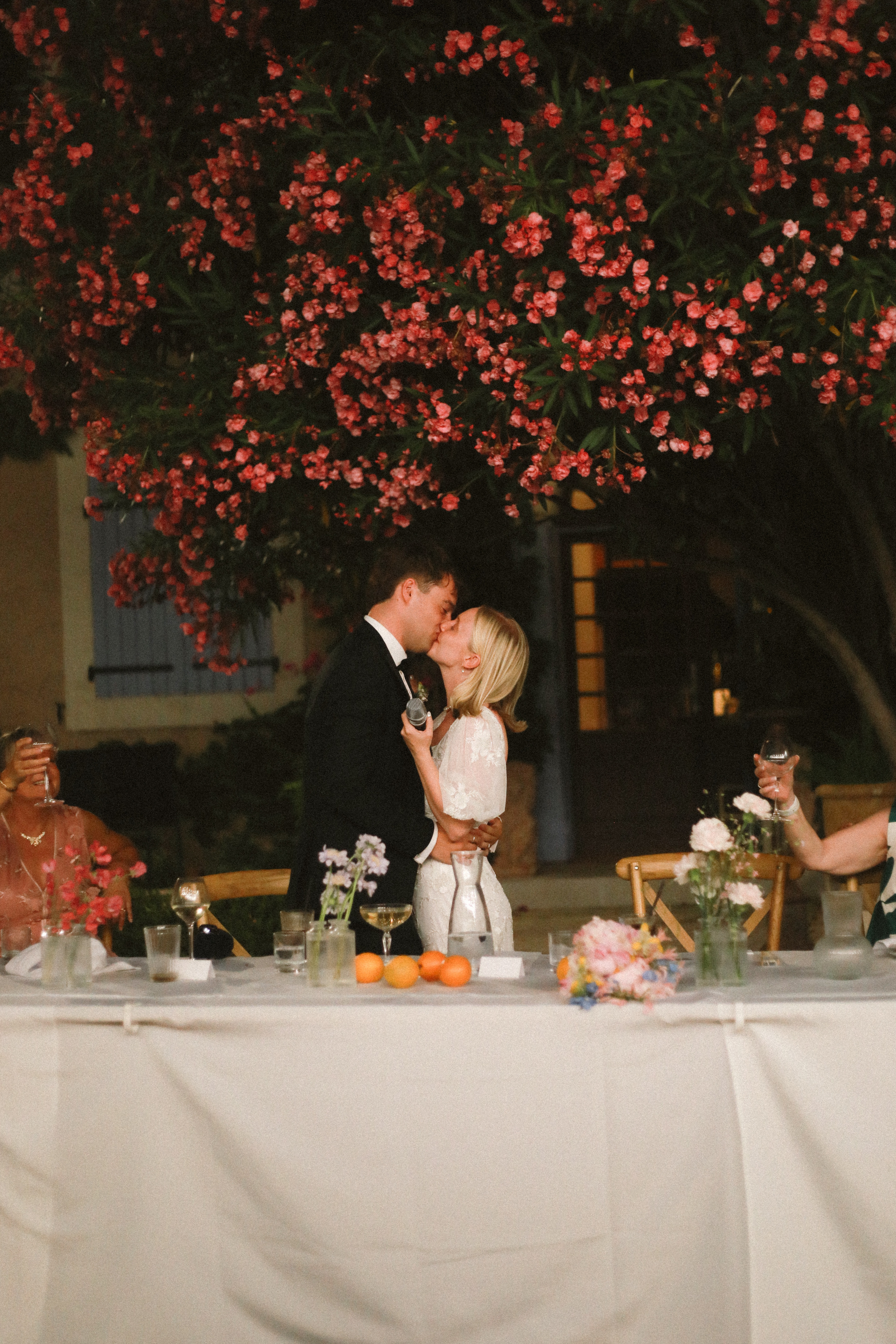 Newlyweds kiss at top table beneath pink oleander at Chateau du Puits es Pratx, Ginestas