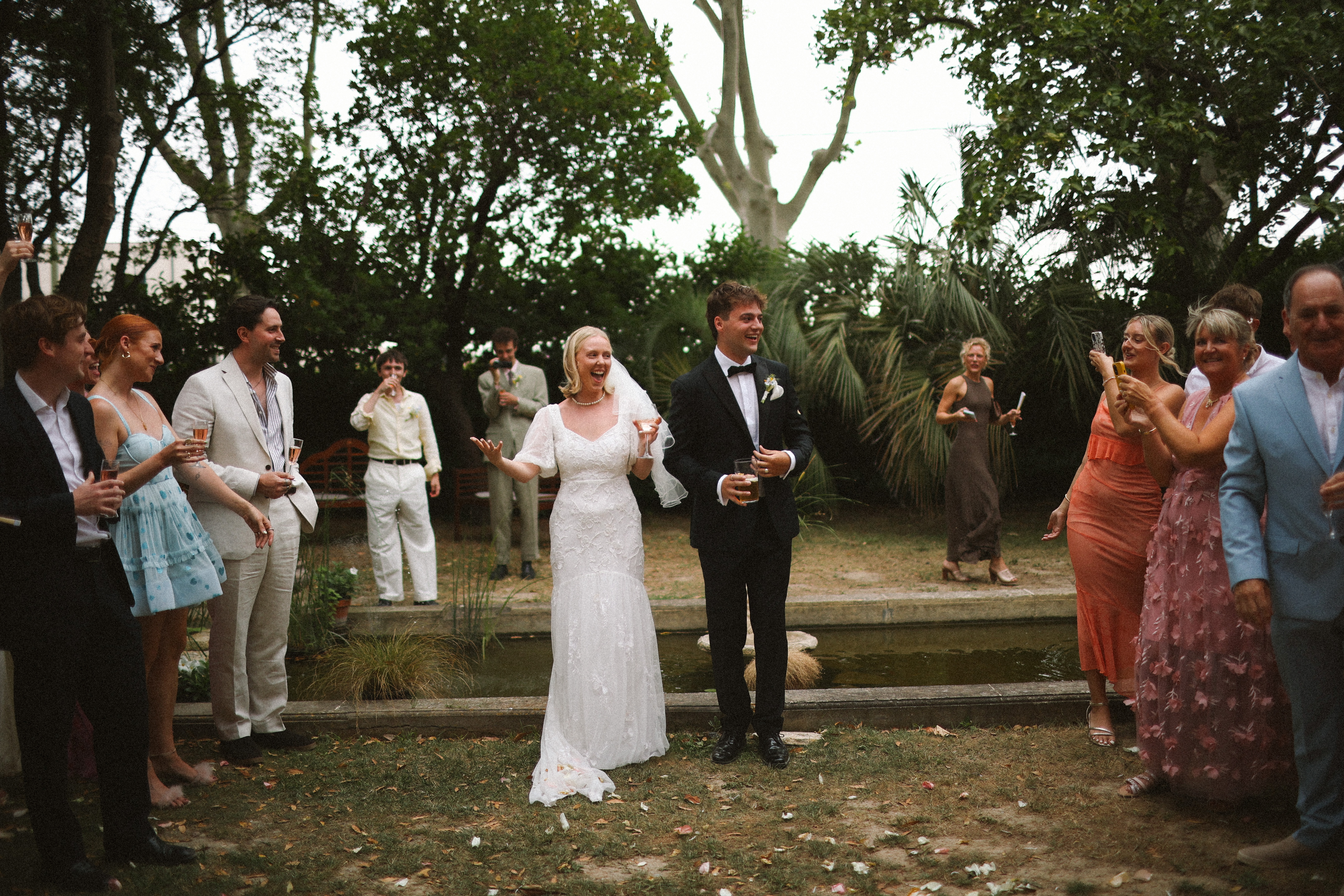 Couple toasting with guests by the pond at Chateau du Puits es Pratx, Ginestas