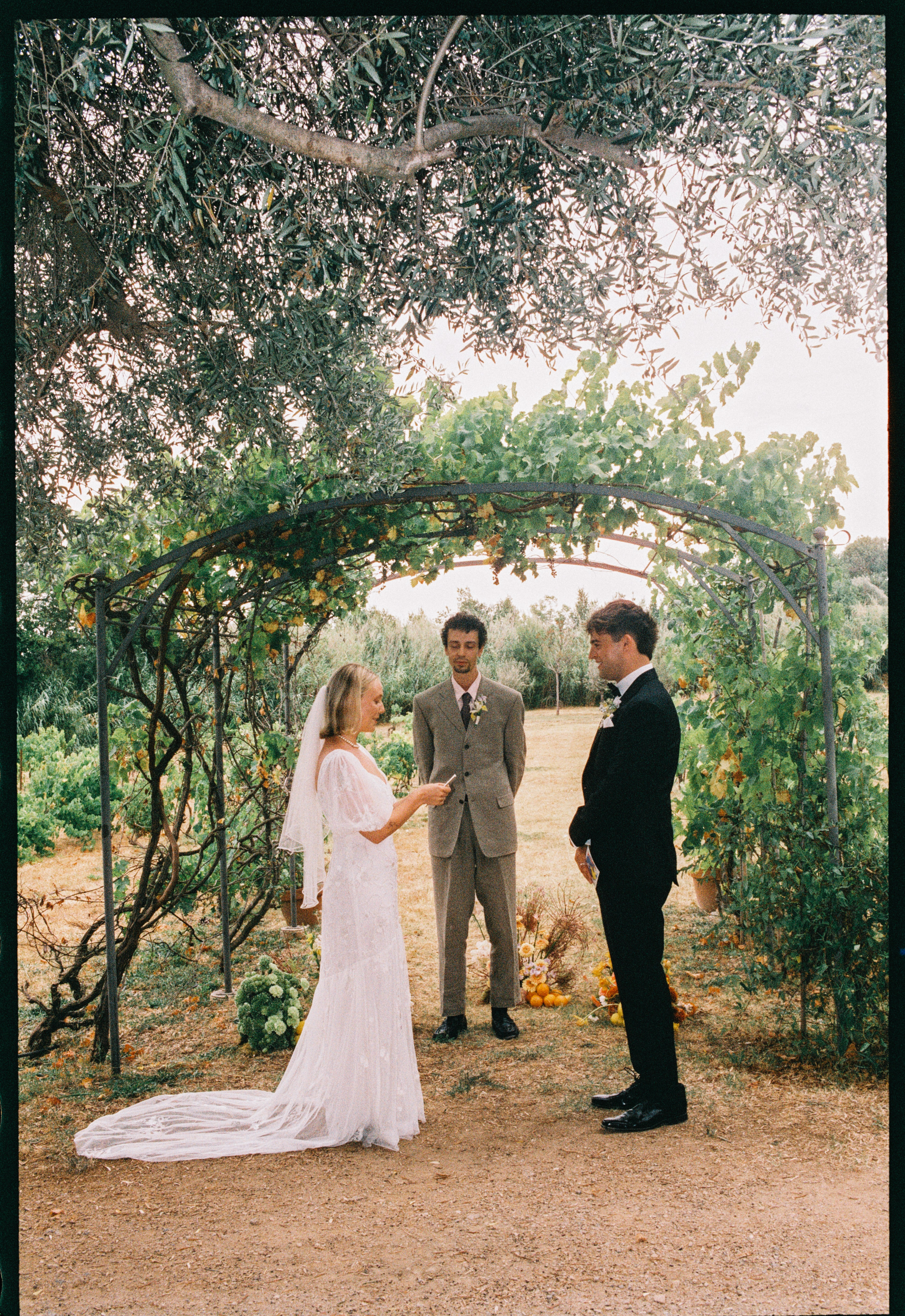 Couple and officiant at vineyard arch at Chateau du Puits es Pratx, Ginestas