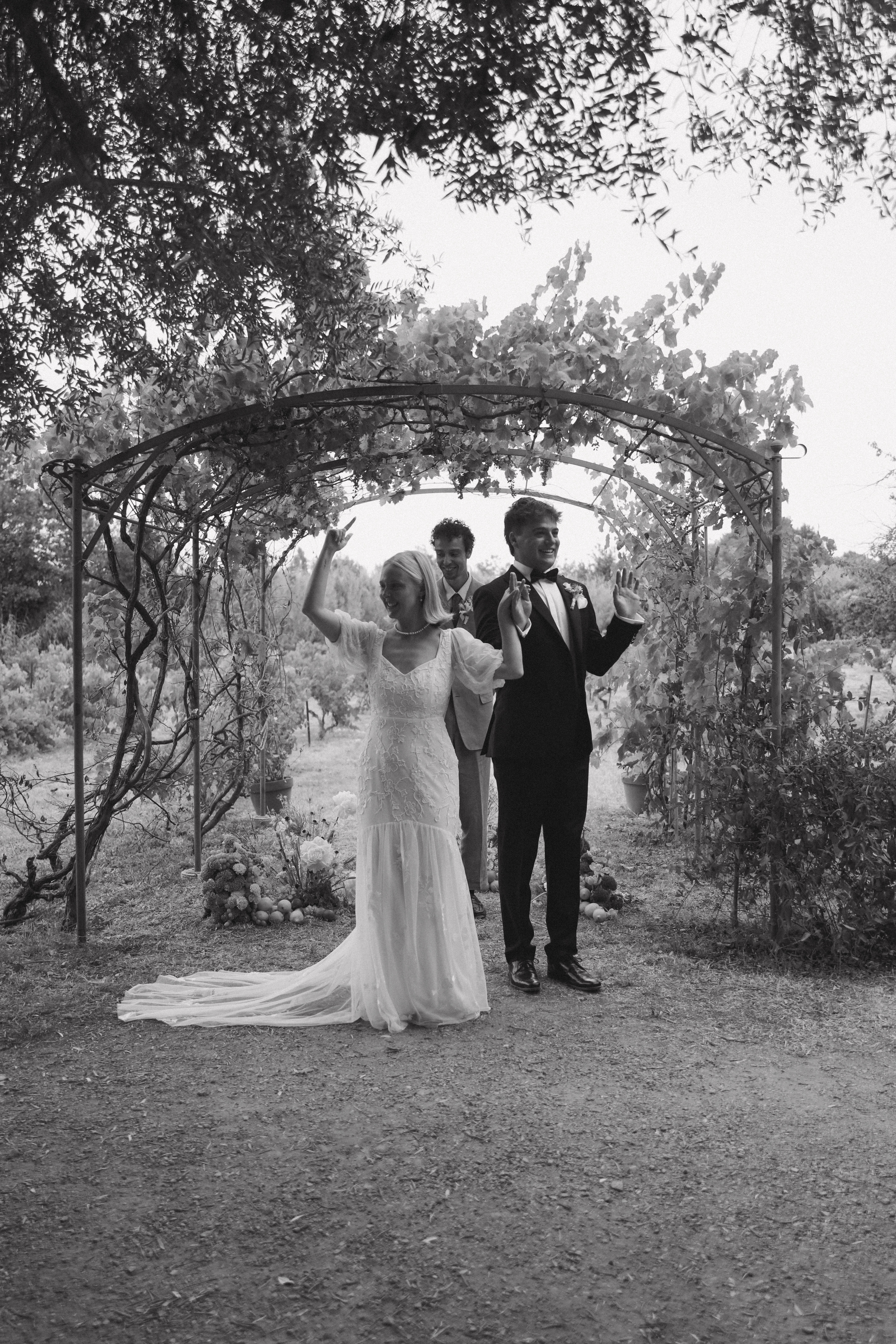 Couple celebrating under vineyard arch in black and white at Chateau du Puits es Pratx, Ginestas